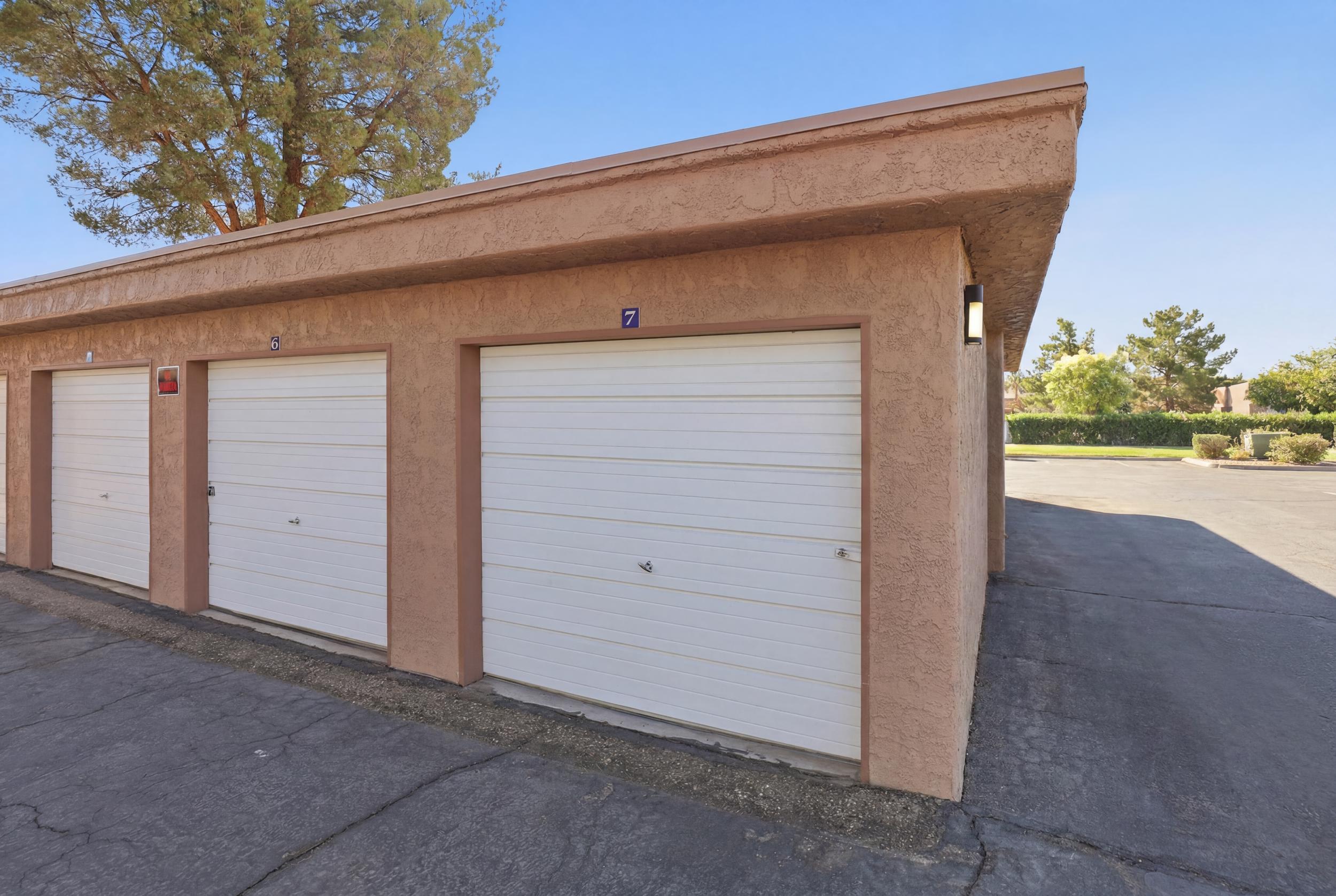 Stucco-finish garage structure featuring multiple individual bays with white paneled doors