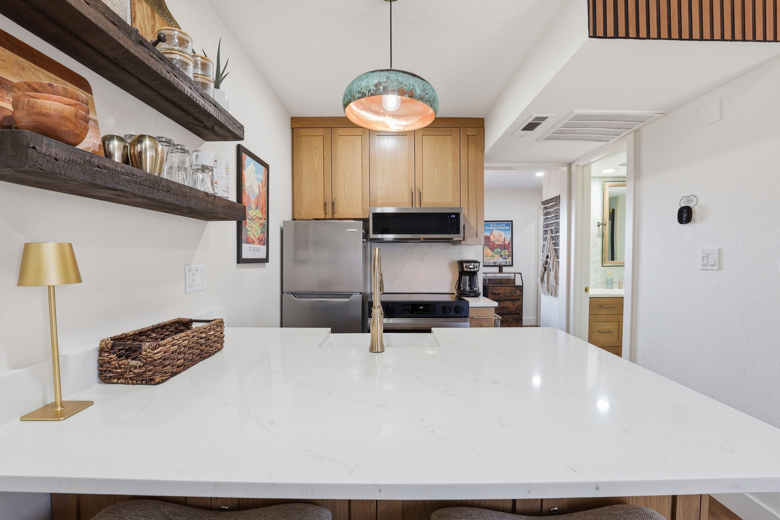 Kitchen featuring a large white countertop island with an integrated sink and gold-finish faucet