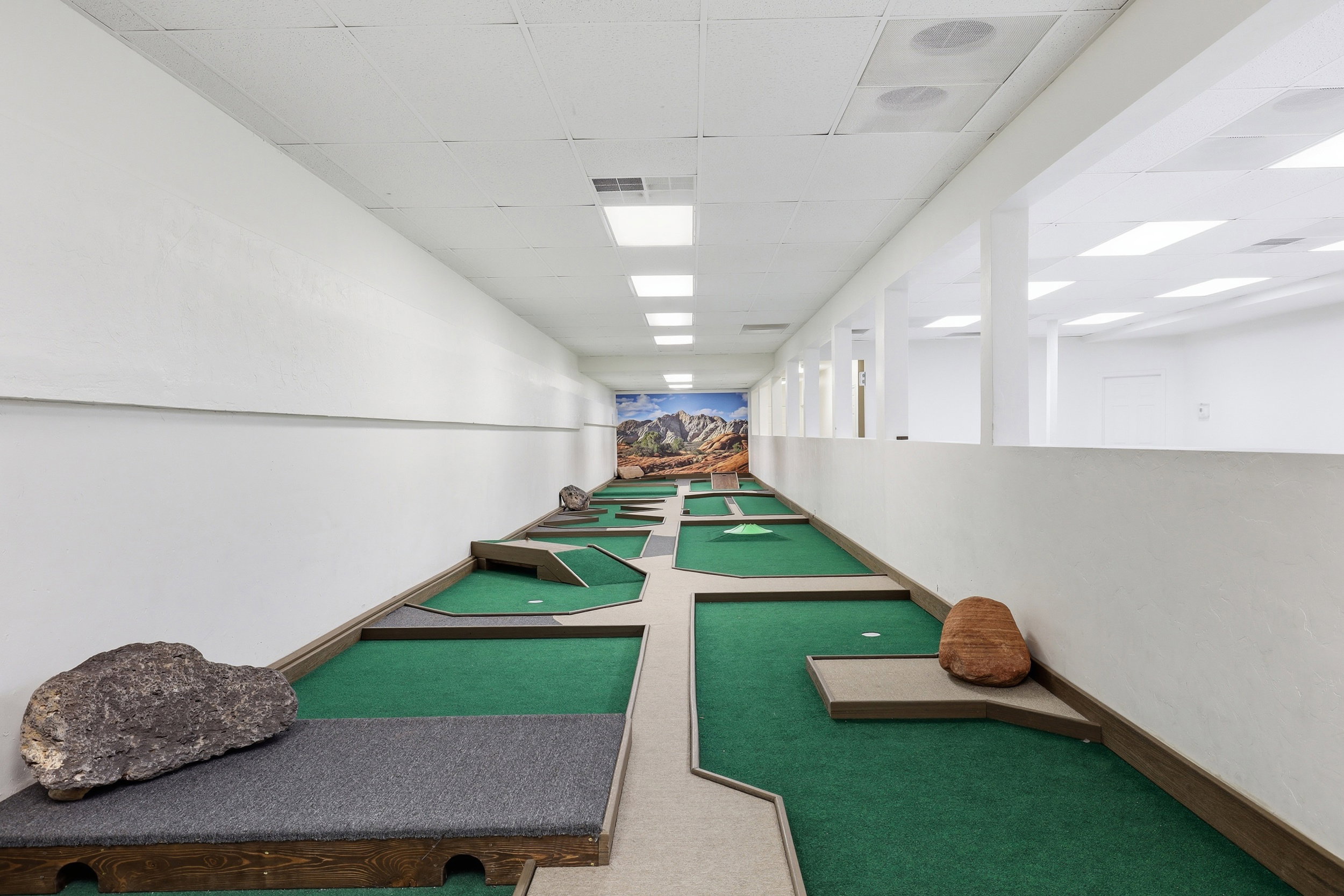 Indoor putting green facility featuring multiple holes and synthetic turf