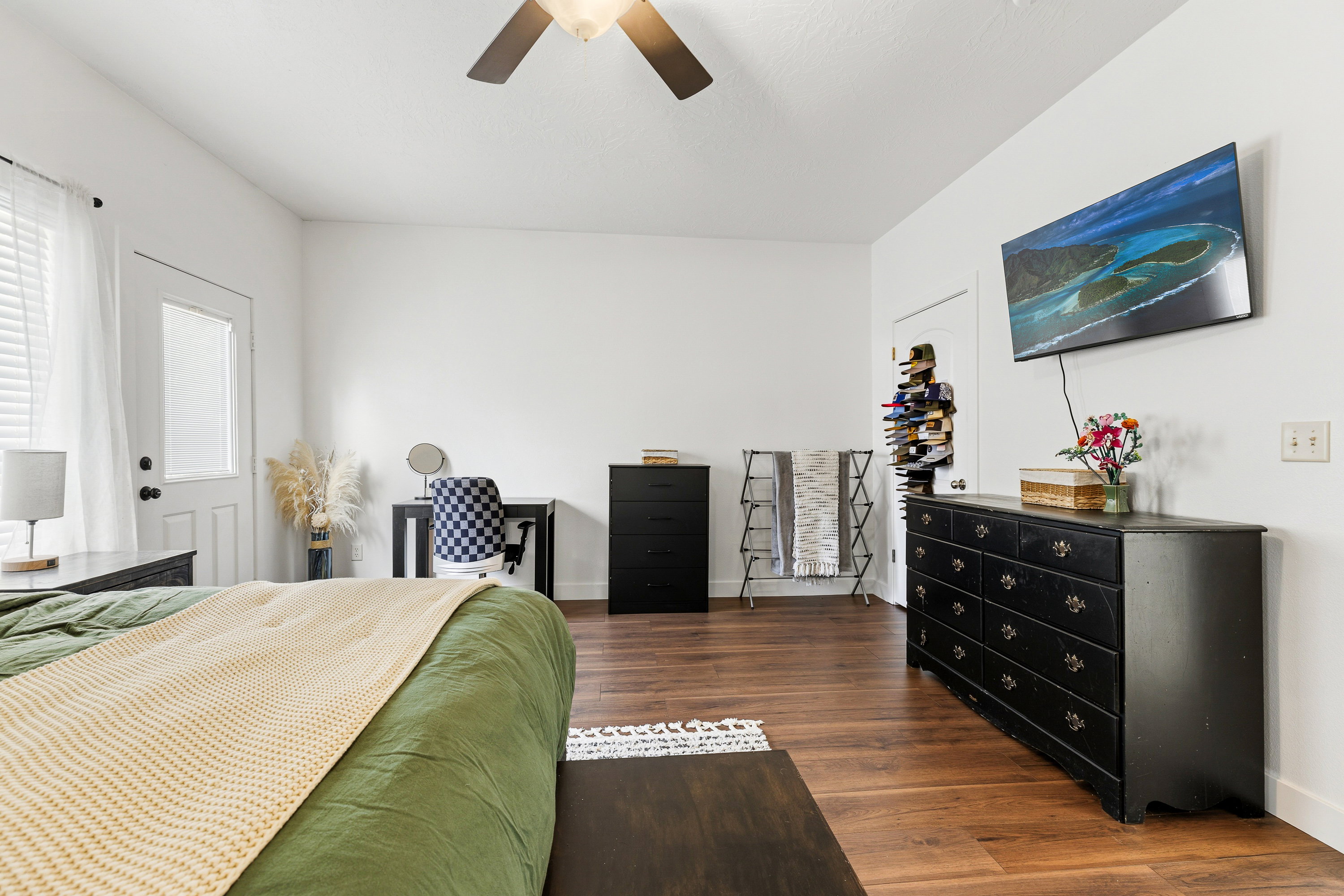 Spacious room featuring wood-finish flooring, white walls, and a ceiling fan