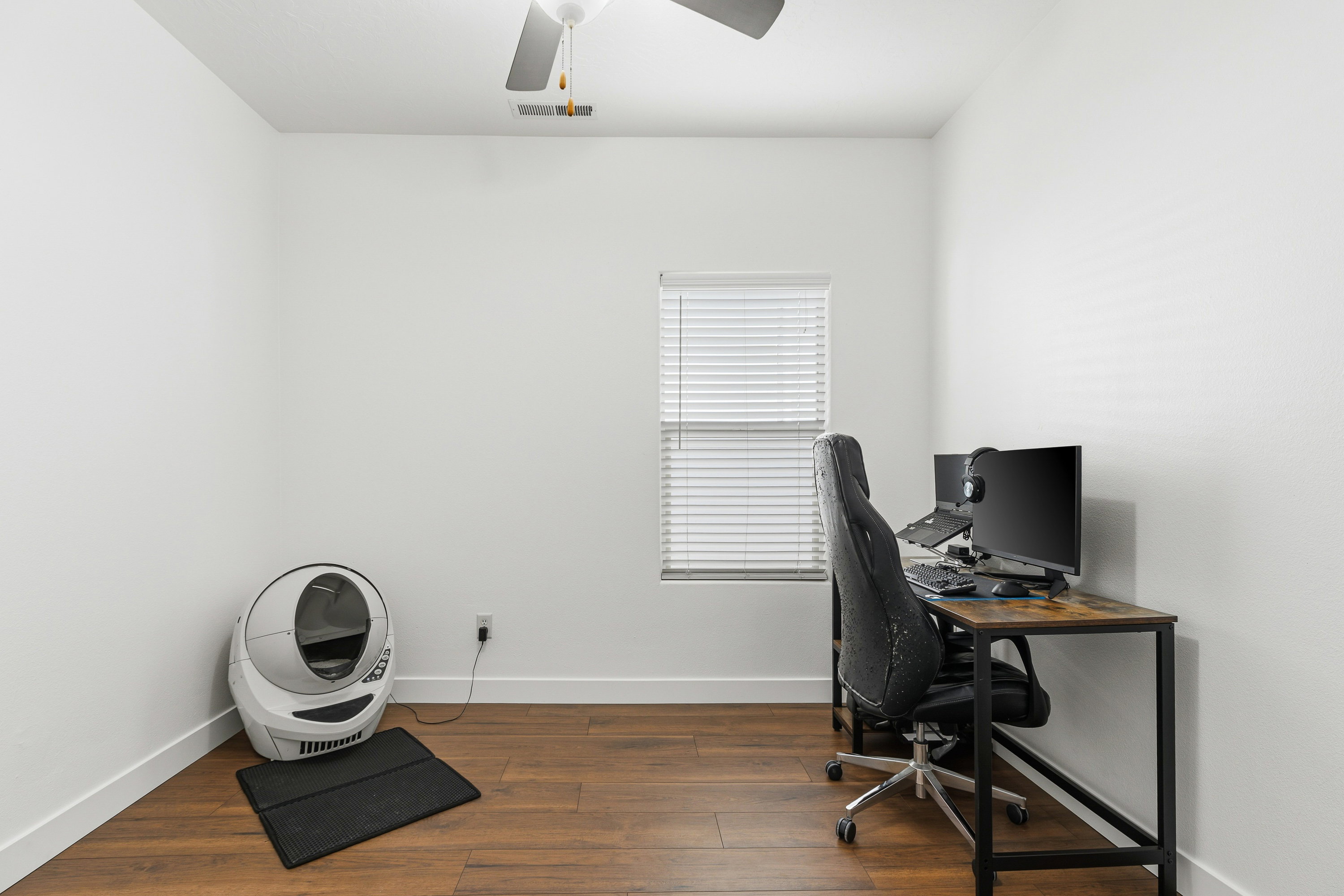 Room featuring wood-finish flooring, a white ceiling with a ceiling fan, and white walls