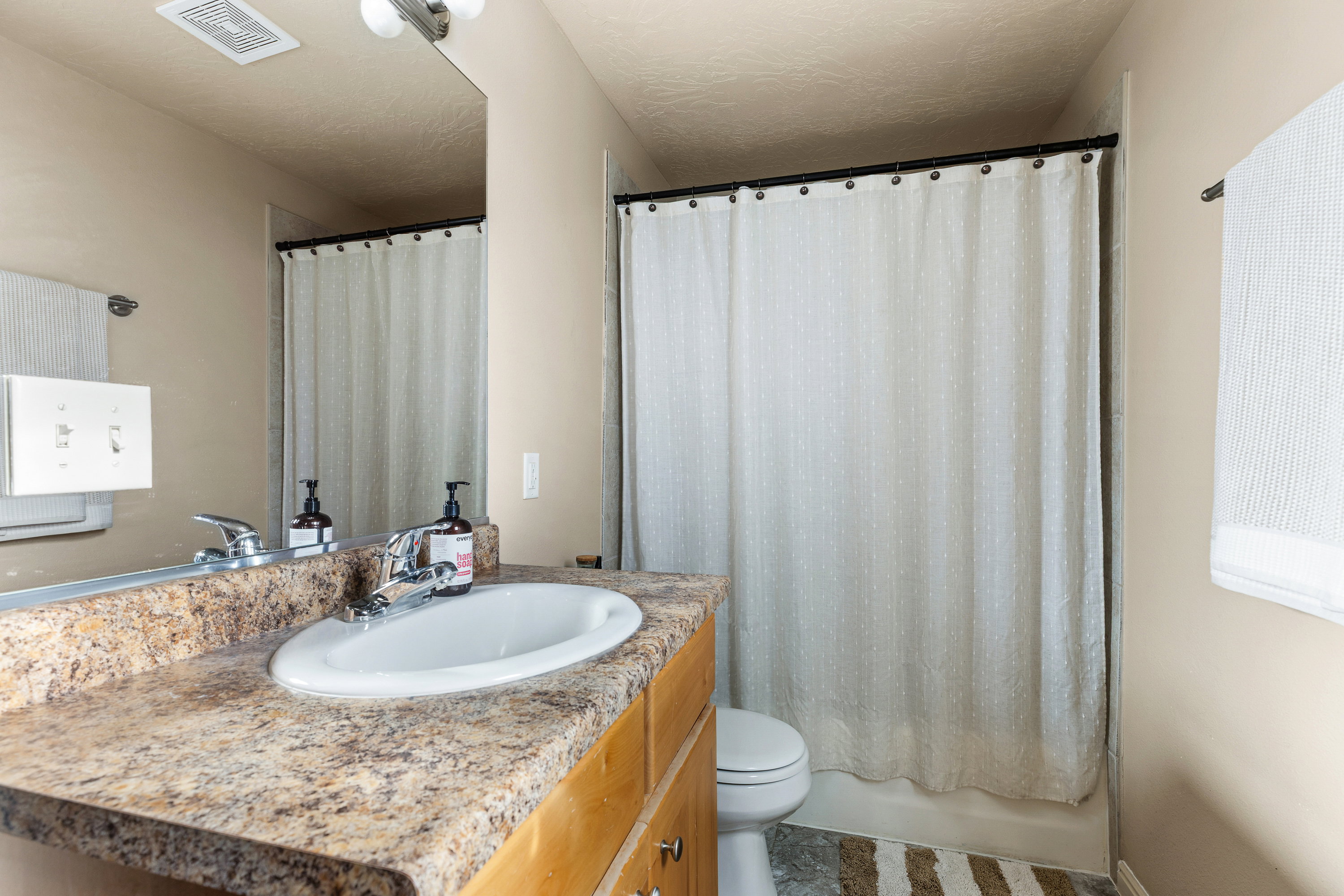 Bathroom featuring a vanity with a laminate countertop, an oval undermount sink, and chrome fixtures