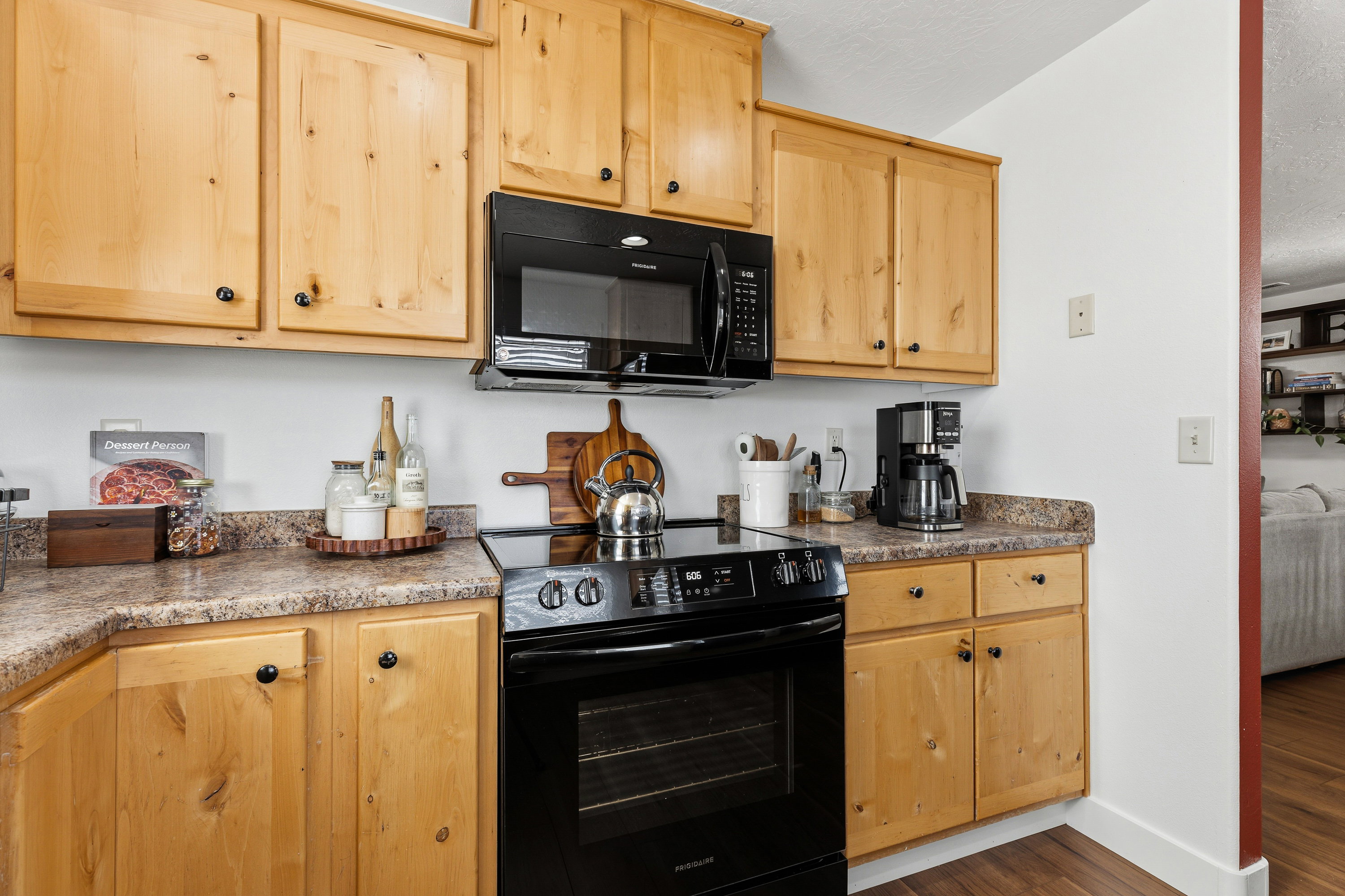 Kitchen featuring ample light wood cabinetry, stone-look countertops, a built-in microwave, and a black electric range with a smooth cooktop