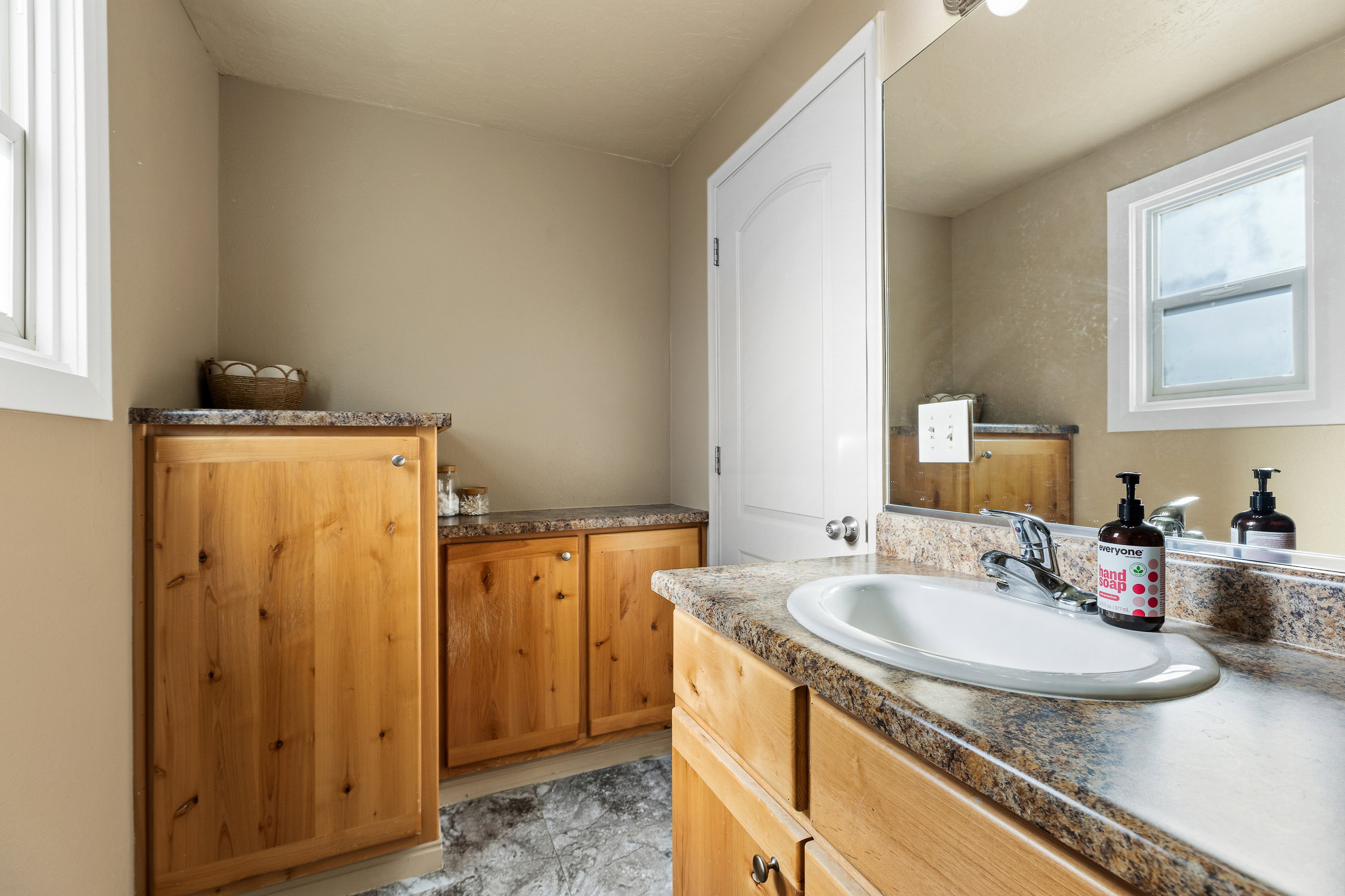 Bathroom vanity with a white oval sink, chrome faucet, and a stone-look countertop