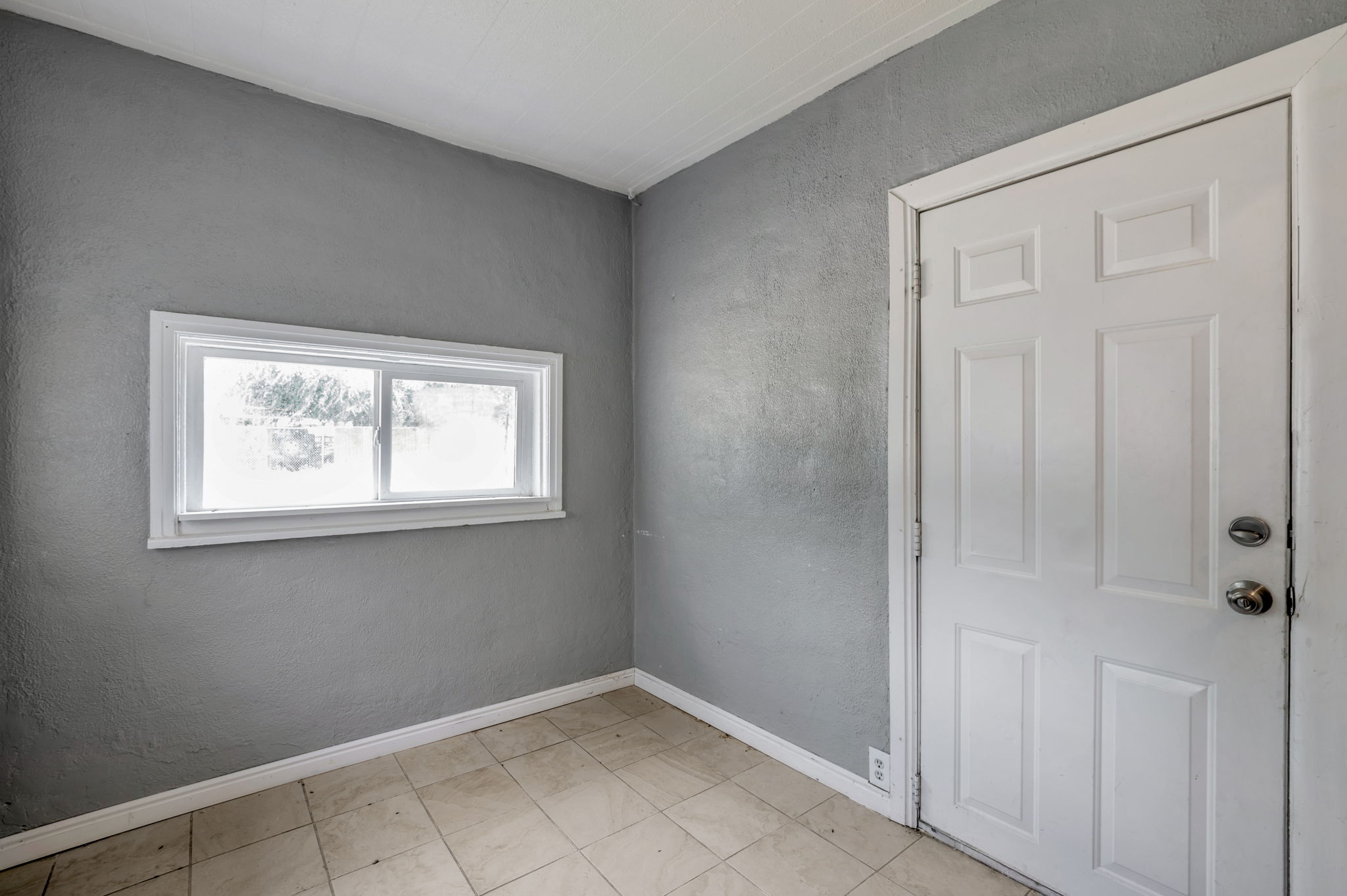 Room featuring neutral gray walls and light-toned floor tiling