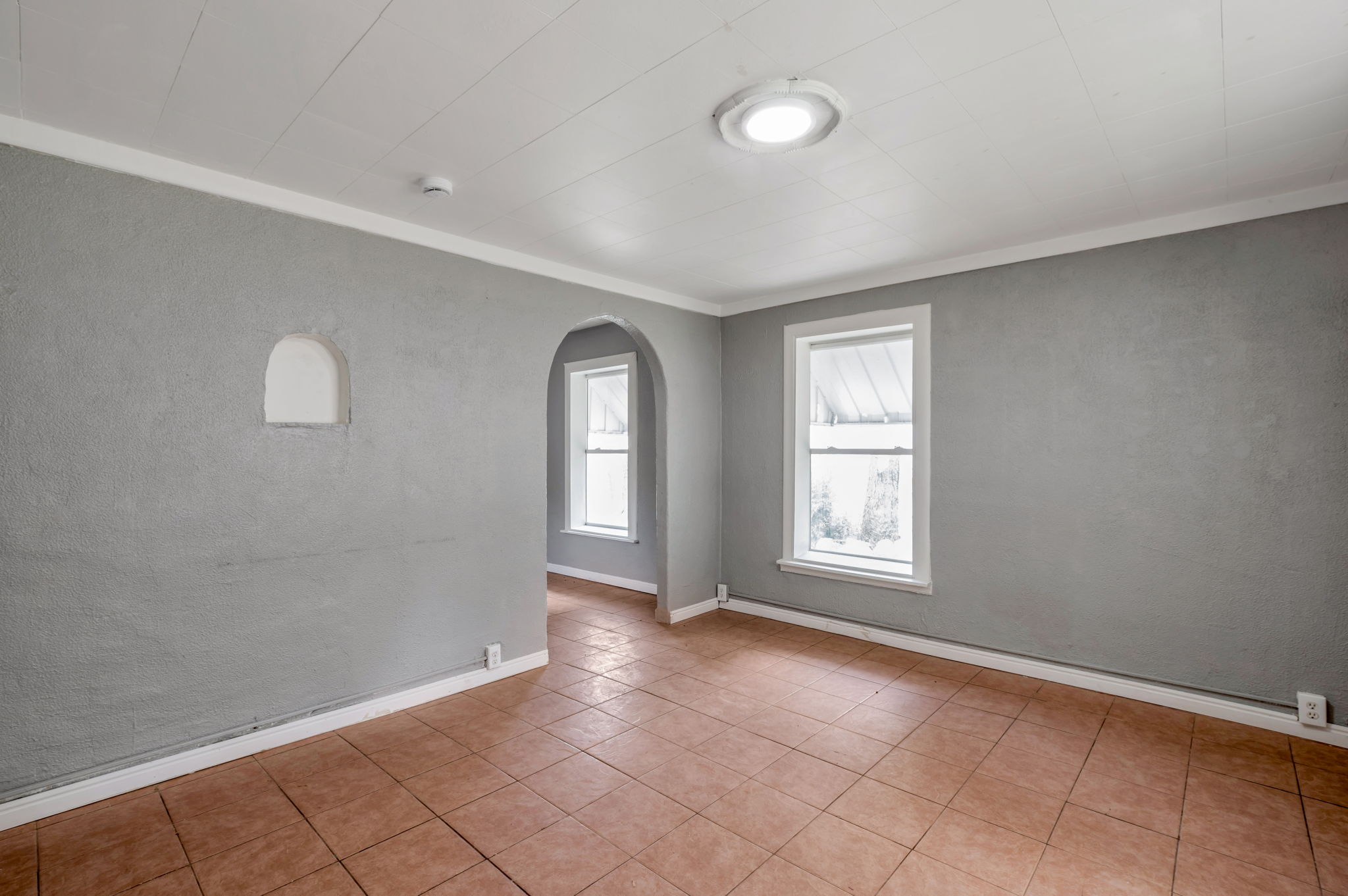 Room featuring terracotta-style tile flooring, textured gray walls, and white trim