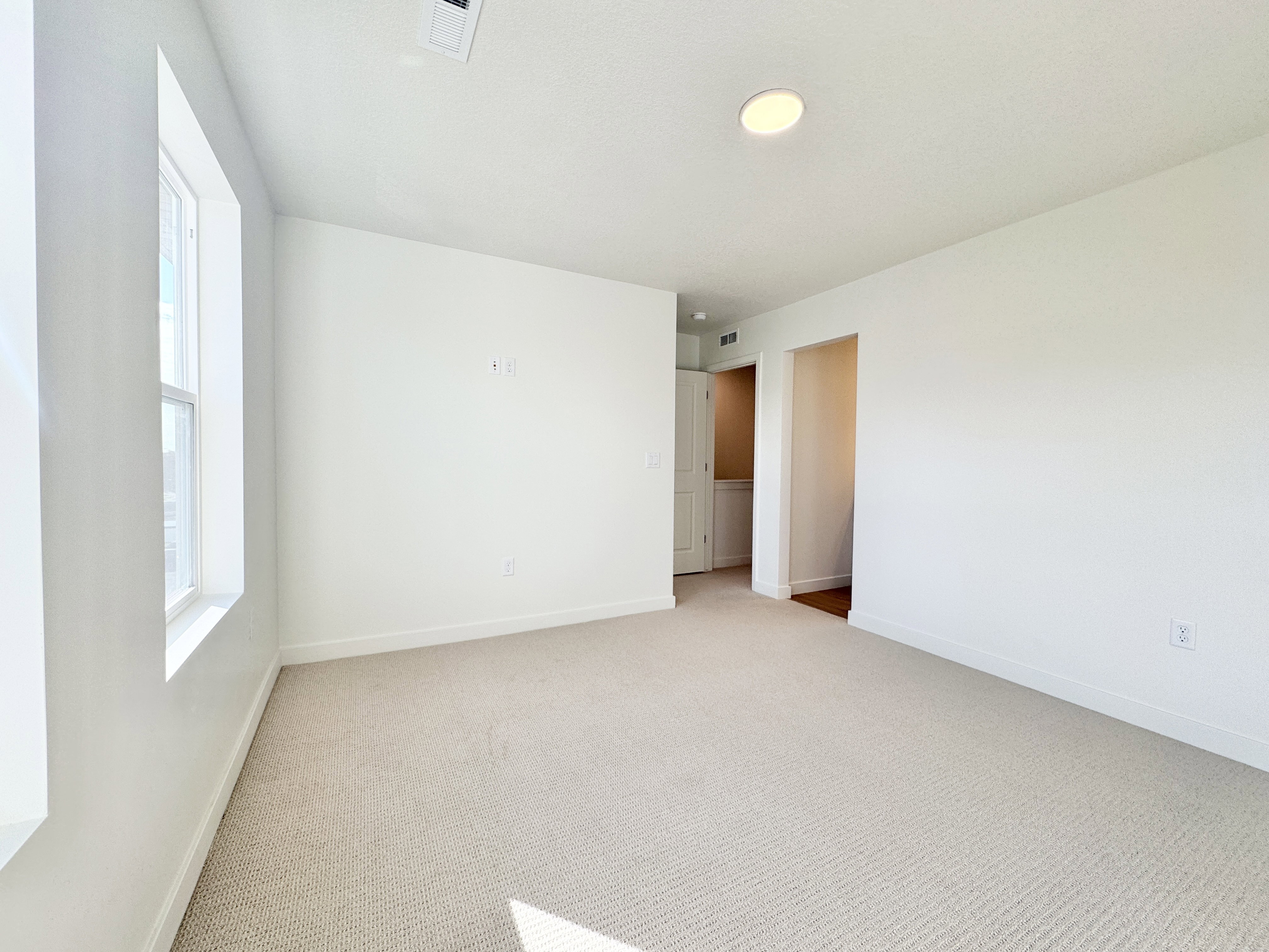 Spacious room featuring neutral carpeting and white walls