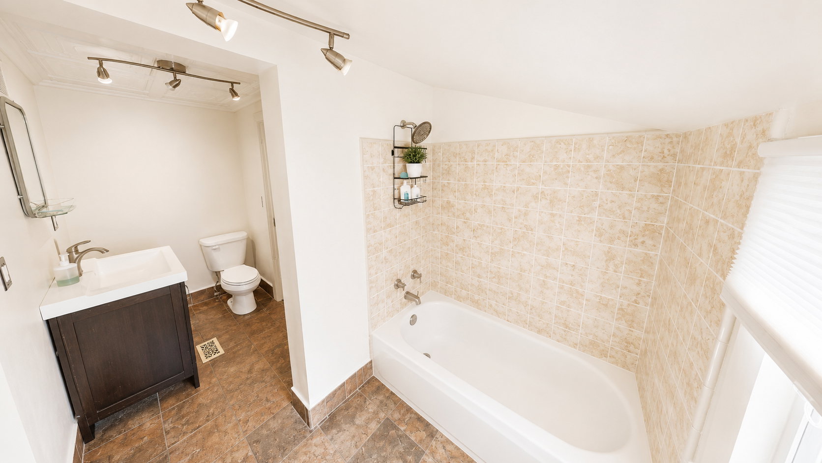 Full bathroom featuring a dark wood-finish vanity with an integrated sink, a white bathtub, and floor-to-ceiling tiled shower surround