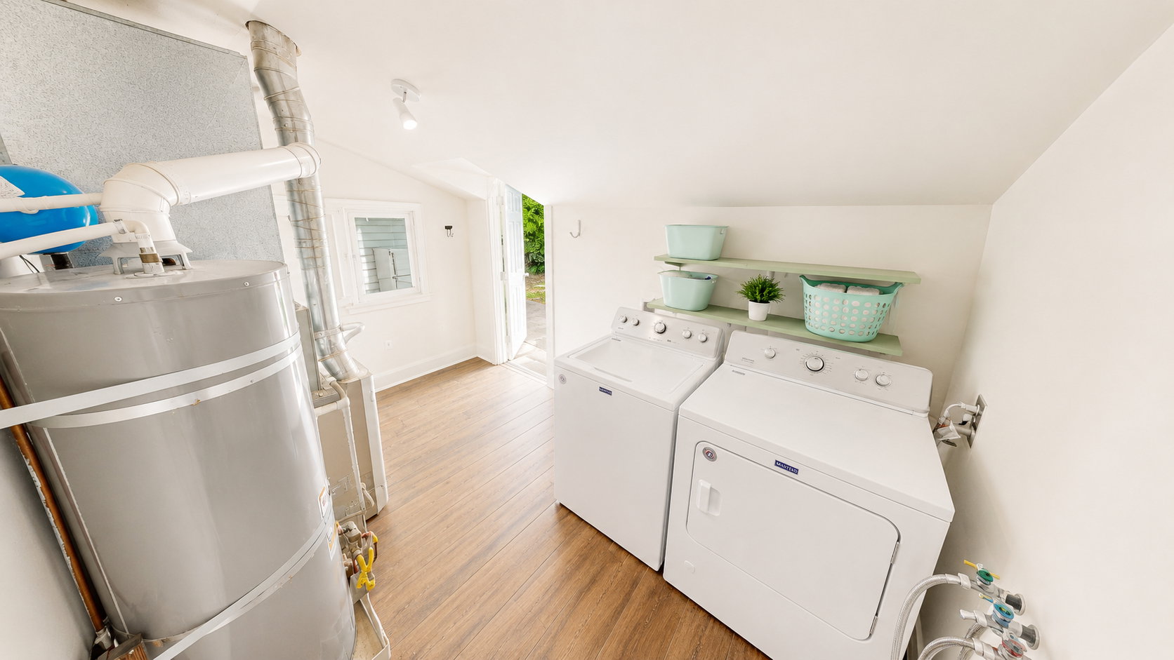 Utility room featuring wood-finish flooring, a water heater, and wall shelving