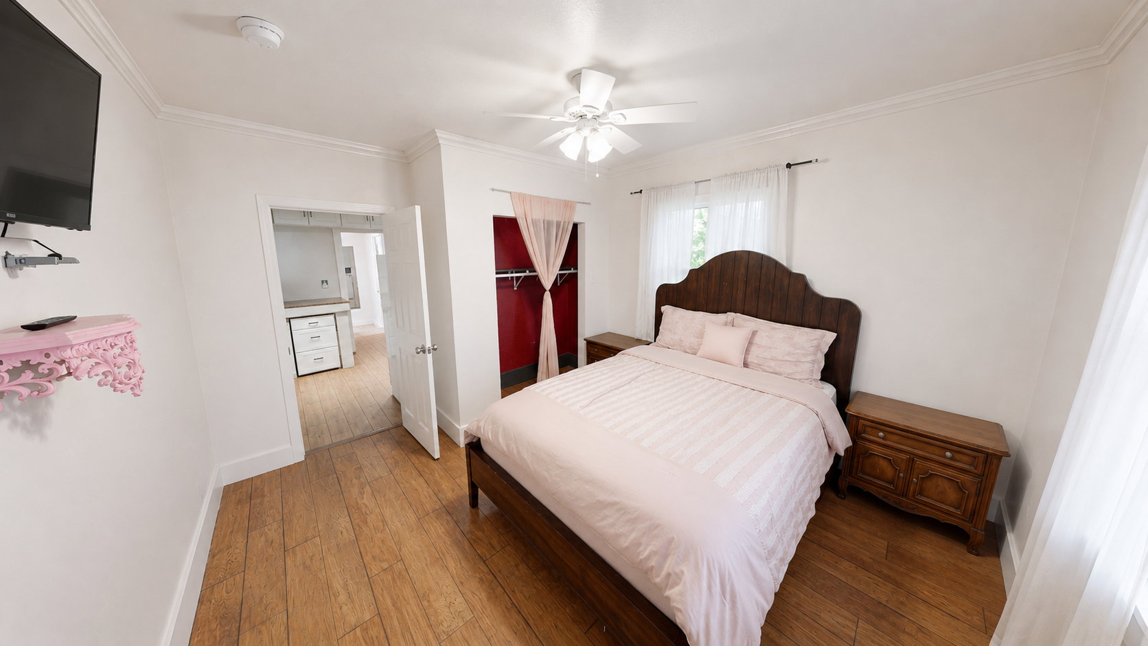 Spacious room featuring wood-finish flooring, white walls, and crown molding