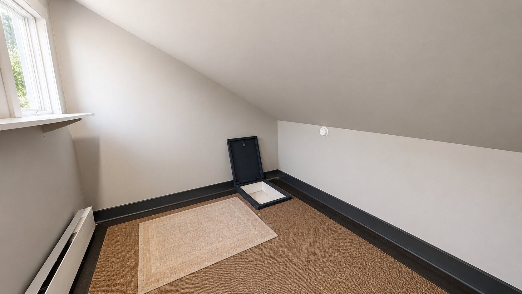 Attic space featuring sloped ceilings, a window with a sill, a built-in floor safe, and wood-finish flooring