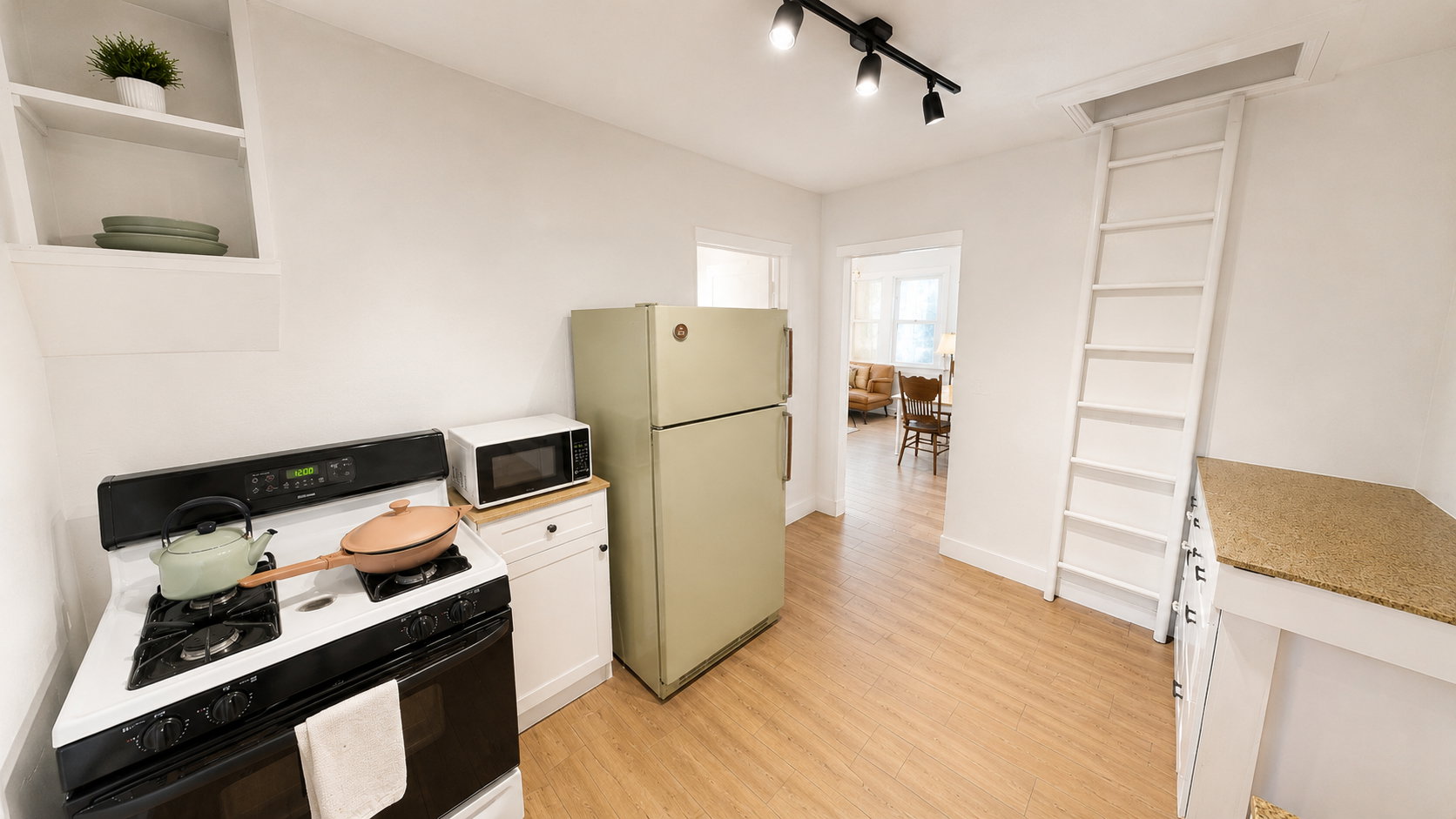 Compact kitchen featuring a white gas range, a vintage-style refrigerator, and a built-in folding ladder for attic access