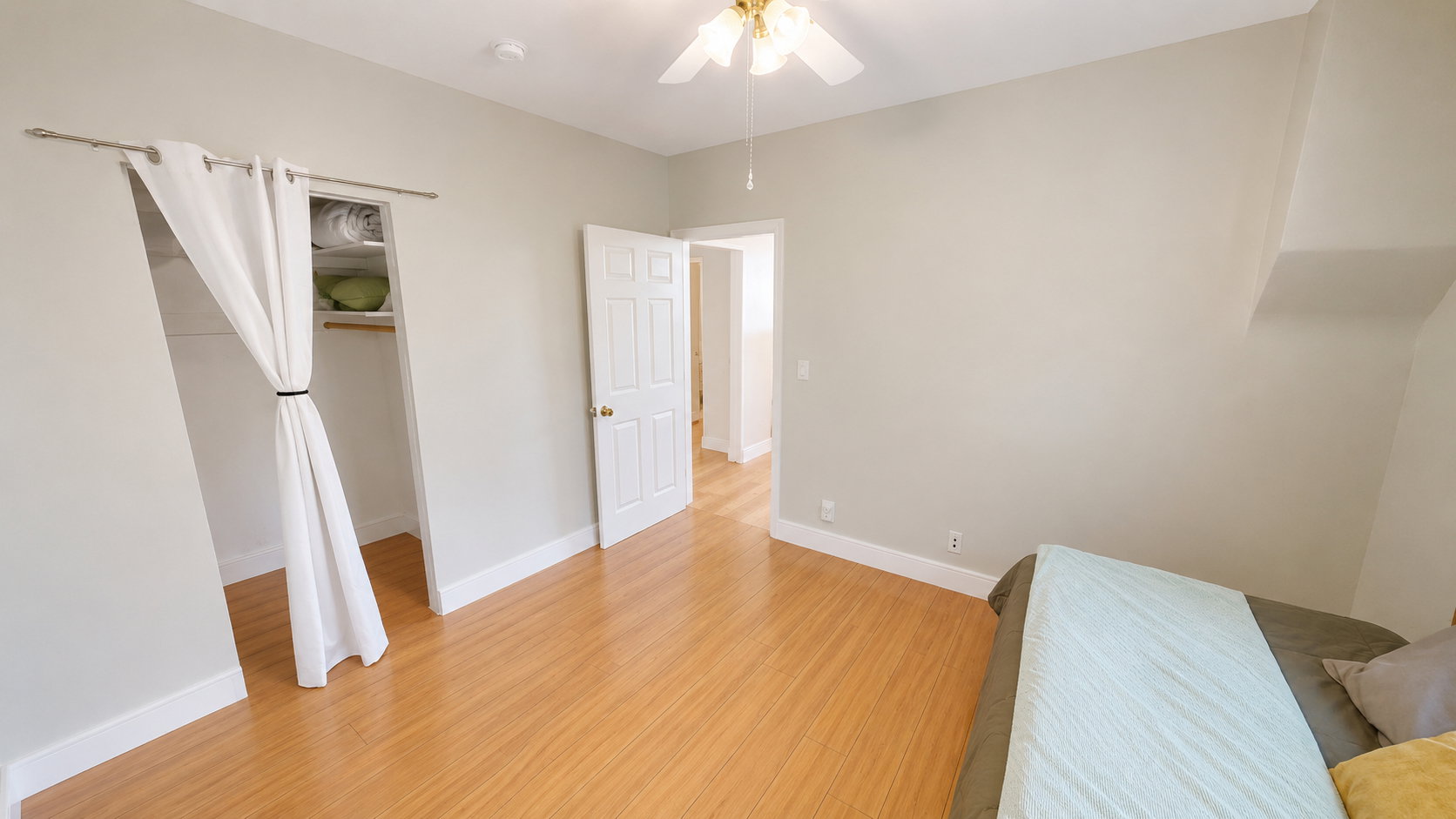 Bedroom featuring wood-finish flooring, light neutral wall paint, and white baseboards
