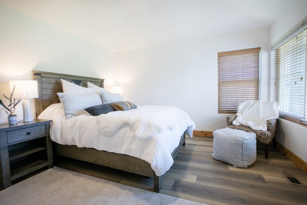 Light-filled room featuring wood-like finish flooring, white walls, and a large window with horizontal blinds