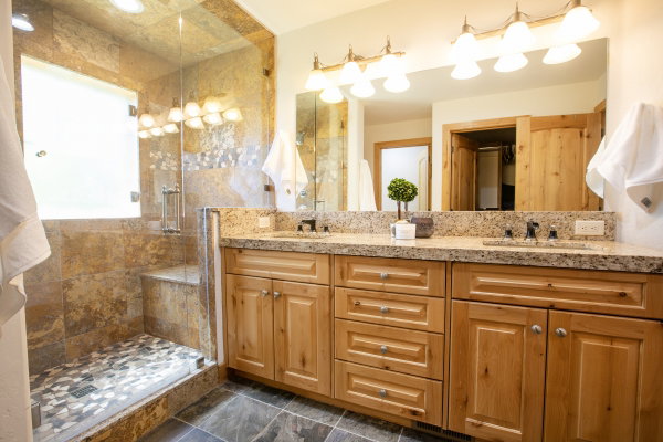 Dual vanity with granite countertops, light wood cabinetry, and brushed nickel hardware
