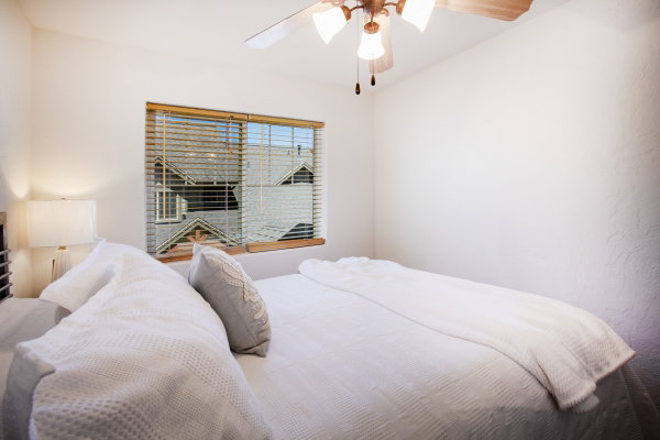 Bedroom featuring a ceiling fan with integrated lighting, a window with wood-finish blinds, and a neutral color palette