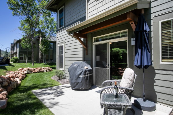 Rear patio featuring a sliding glass door with screen, board and batten siding, and a landscaped rock border