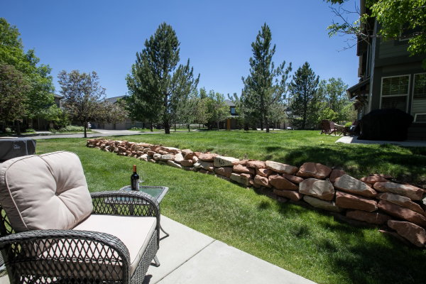 Concrete patio with a stone retaining wall and a verdant lawn