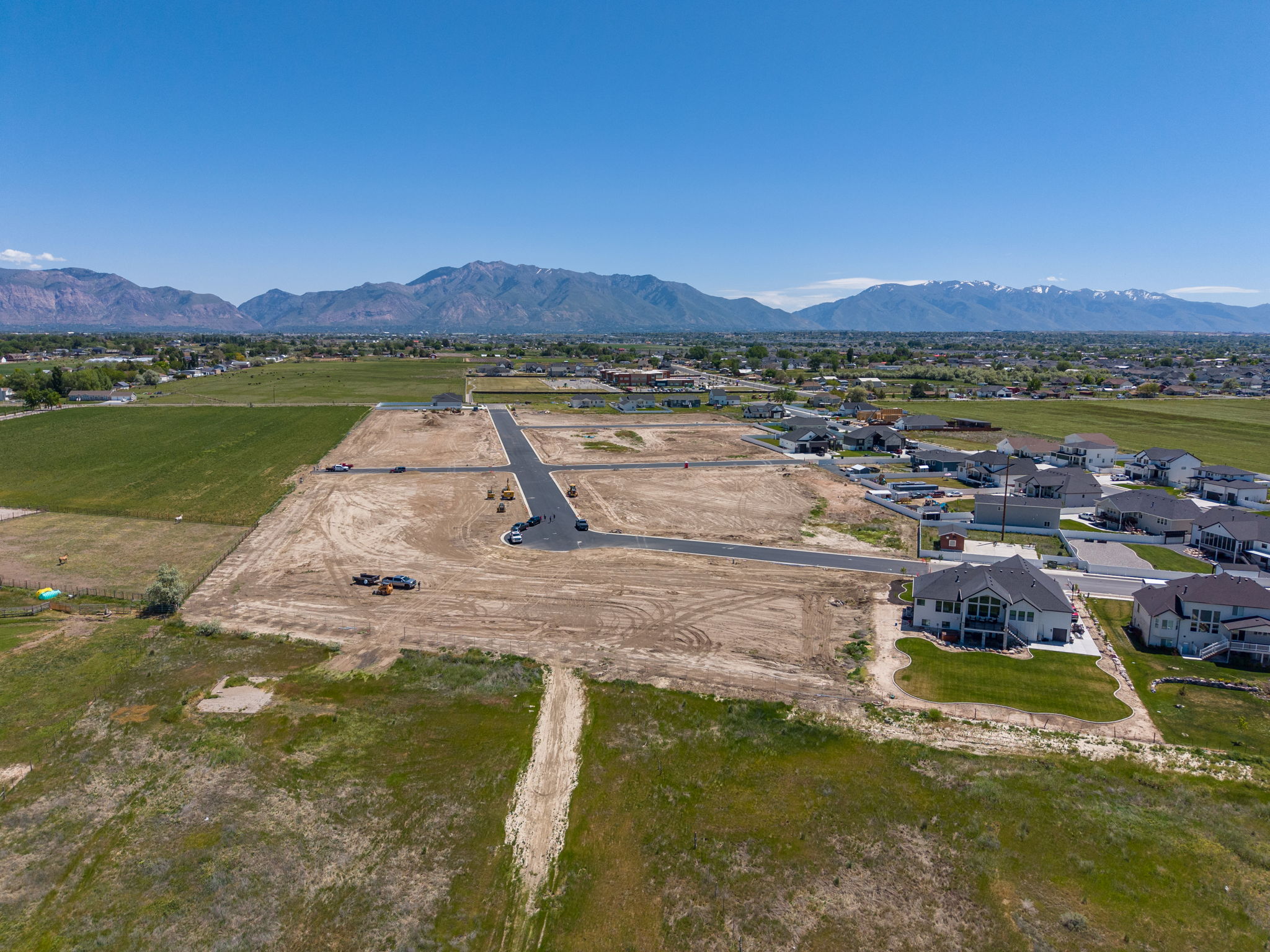 New residential development featuring graded lots and paved streets, surrounded by established homes and agricultural fields