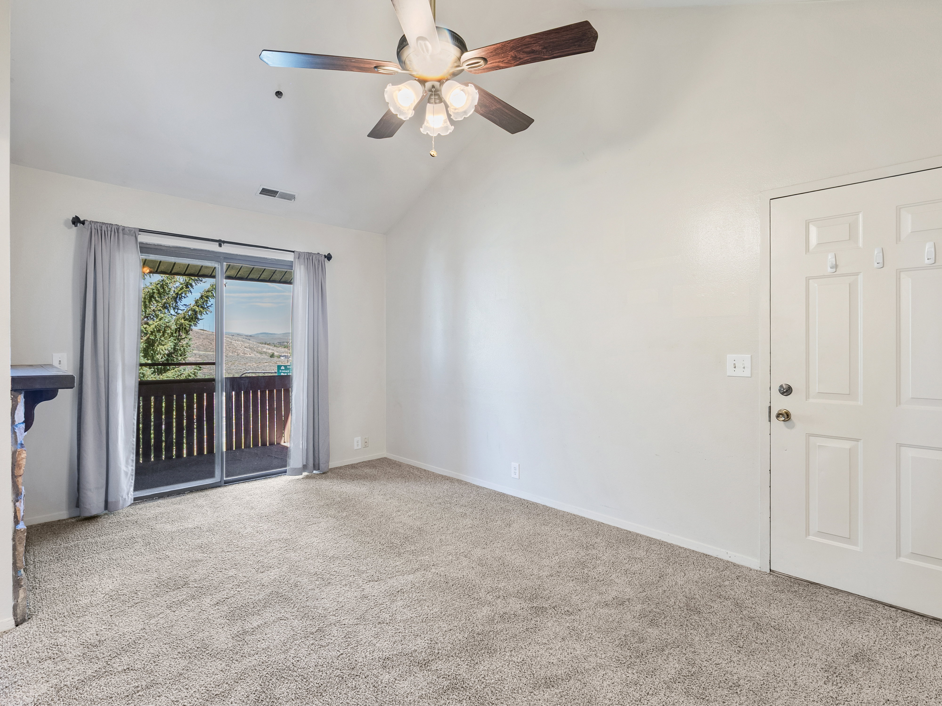 Spacious room featuring vaulted ceilings, light neutral wall paint, and plush carpeting