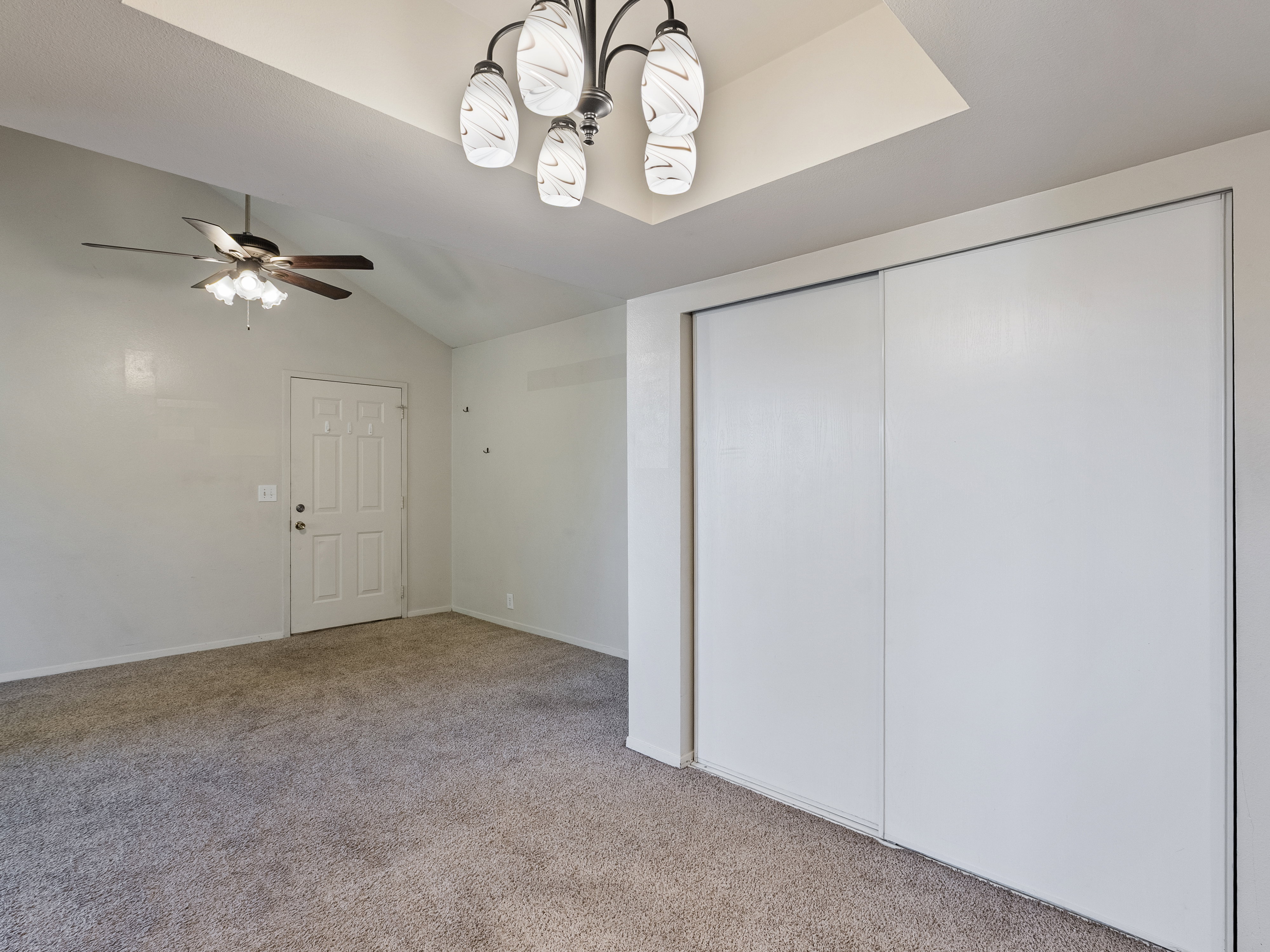 Vaulted ceiling featuring a decorative chandelier and a ceiling fan