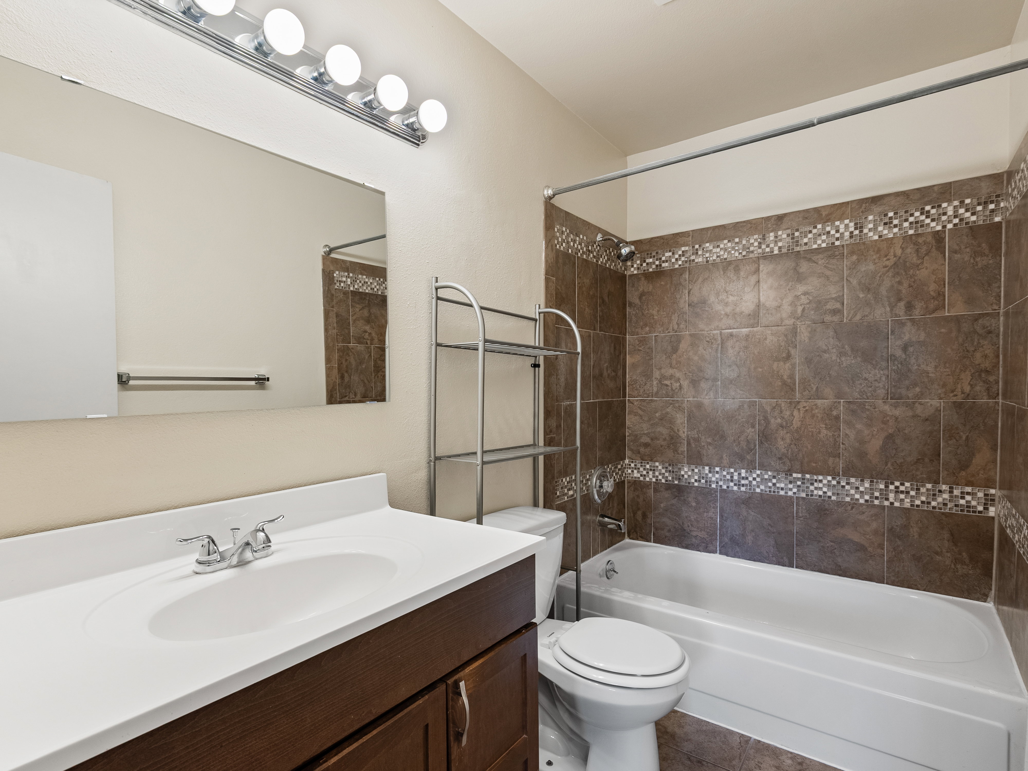 Full bathroom featuring a vanity with a white countertop, chrome faucet, and a large wall-mounted mirror