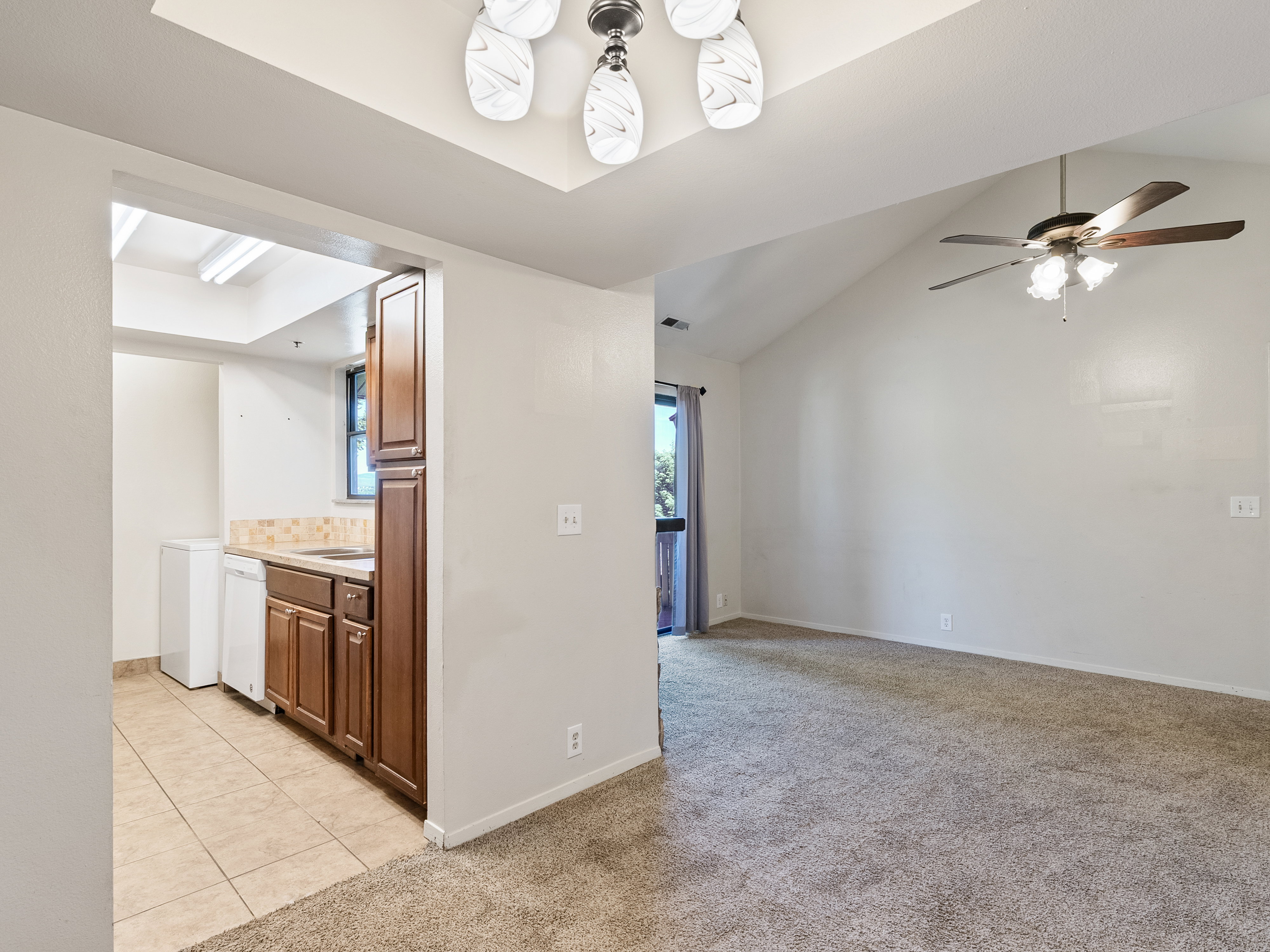 Living area with vaulted ceiling, ceiling fan, and carpet flooring