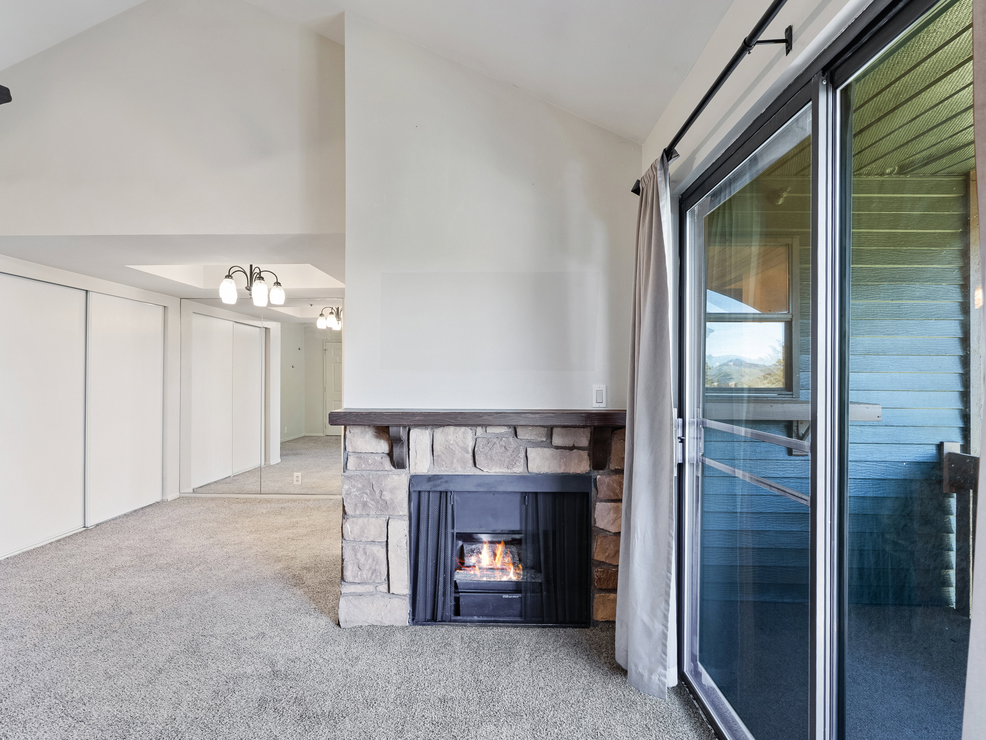 Vaulted ceilings complement a stone-clad fireplace with a wood mantel