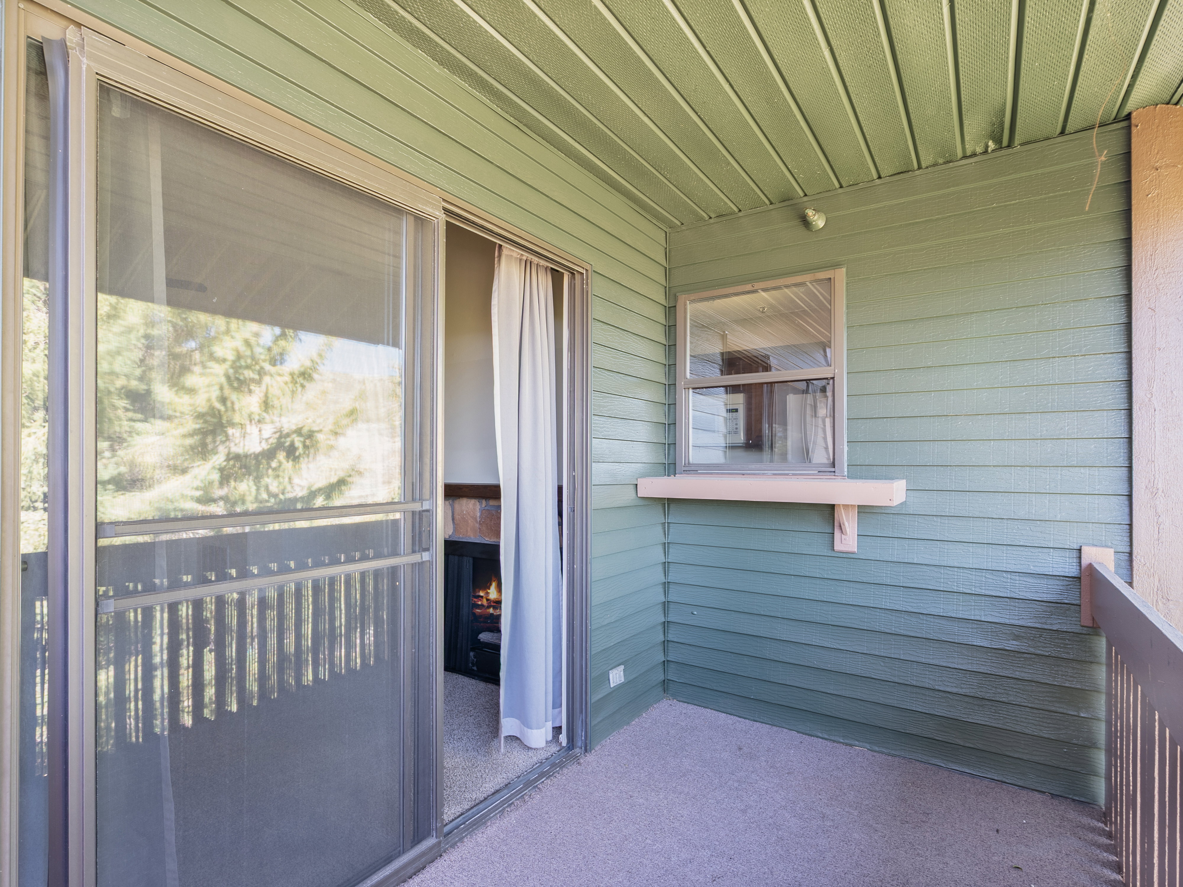 Outdoor balcony featuring light green siding, a sliding glass door, and a built-in window shelf