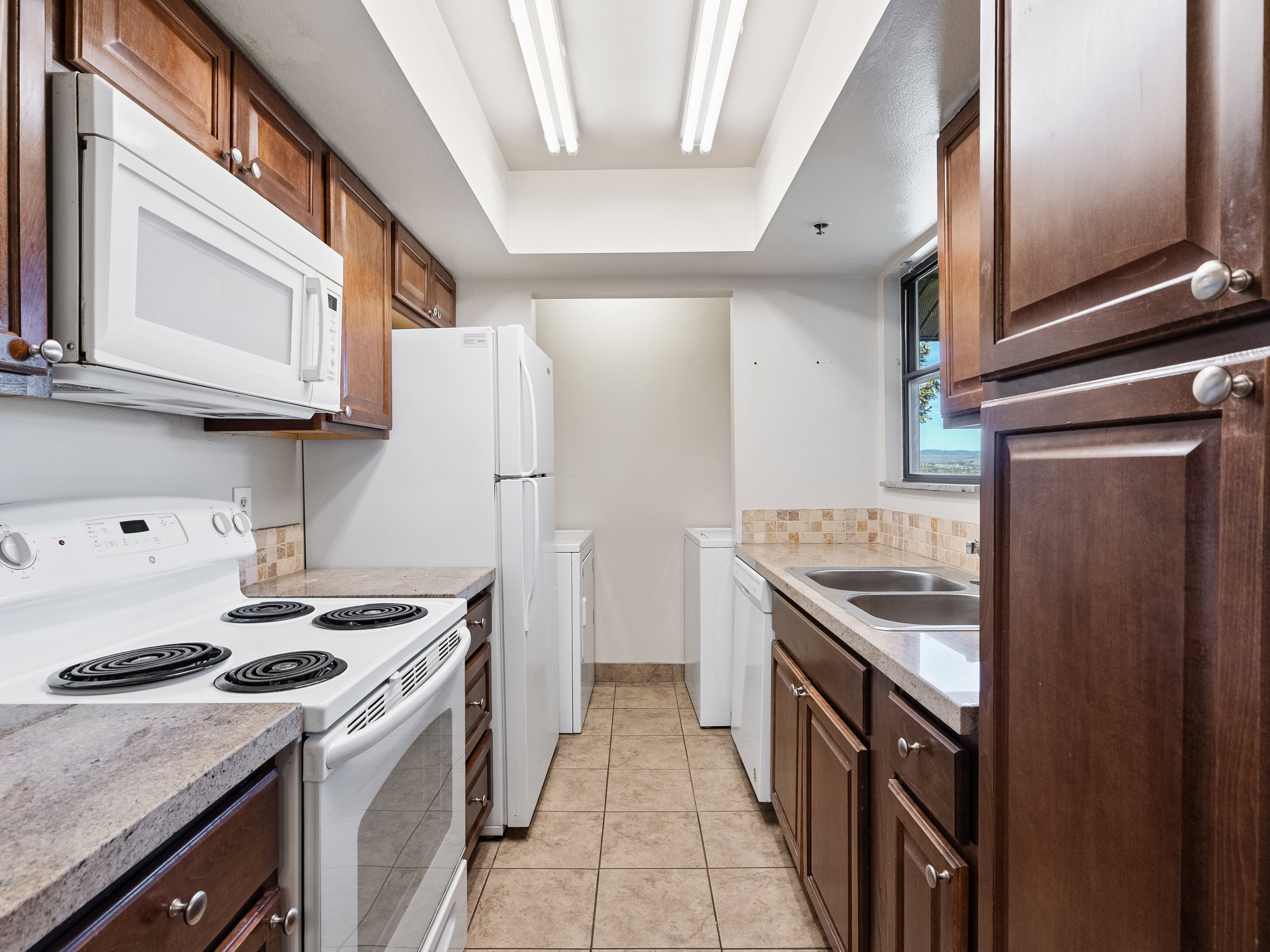 Functional kitchen featuring wood-finish cabinetry, white appliances, and tiled flooring