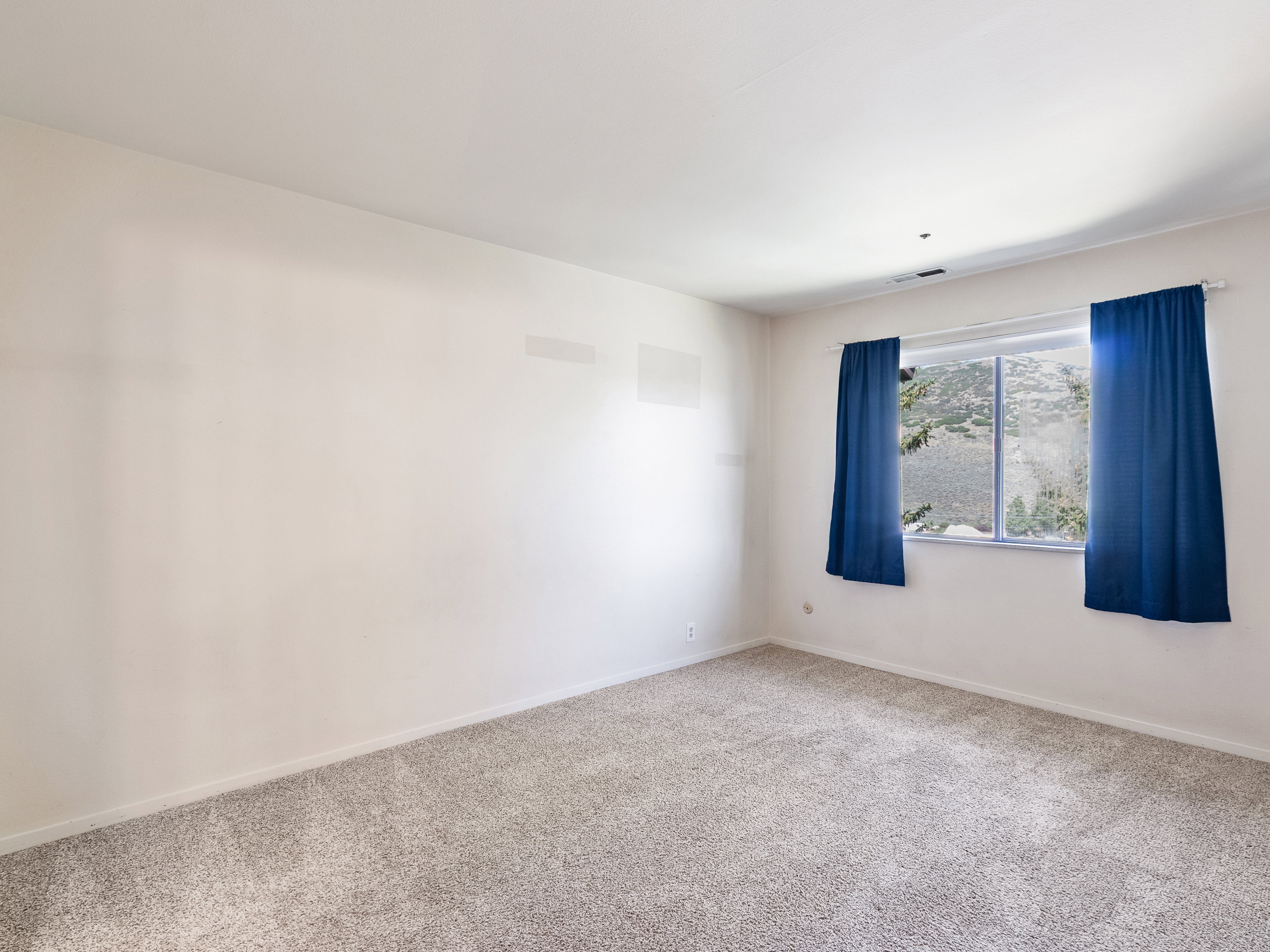 Bright room featuring a window with natural light, neutral wall colors, and light-toned carpet flooring