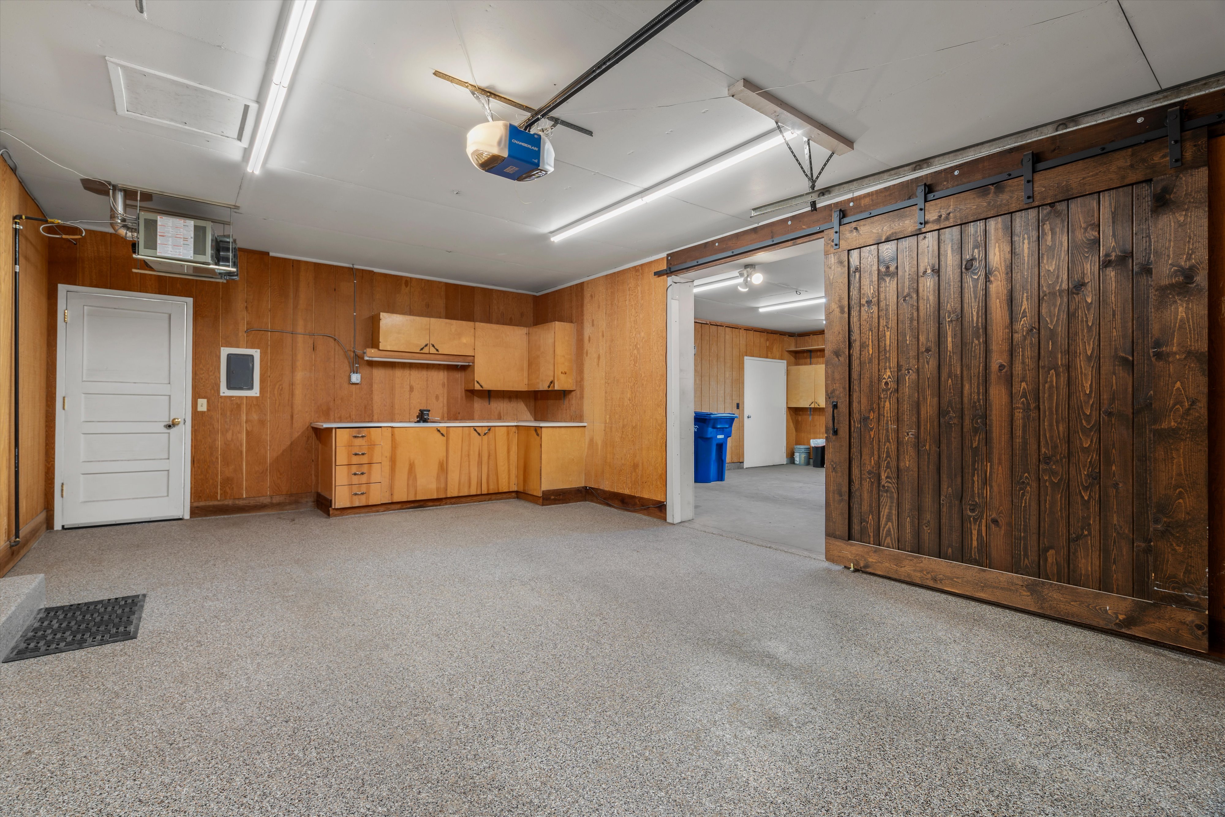 Spacious utility room featuring wood paneling, wood-finish cabinetry, a built-in countertop, and epoxy flooring