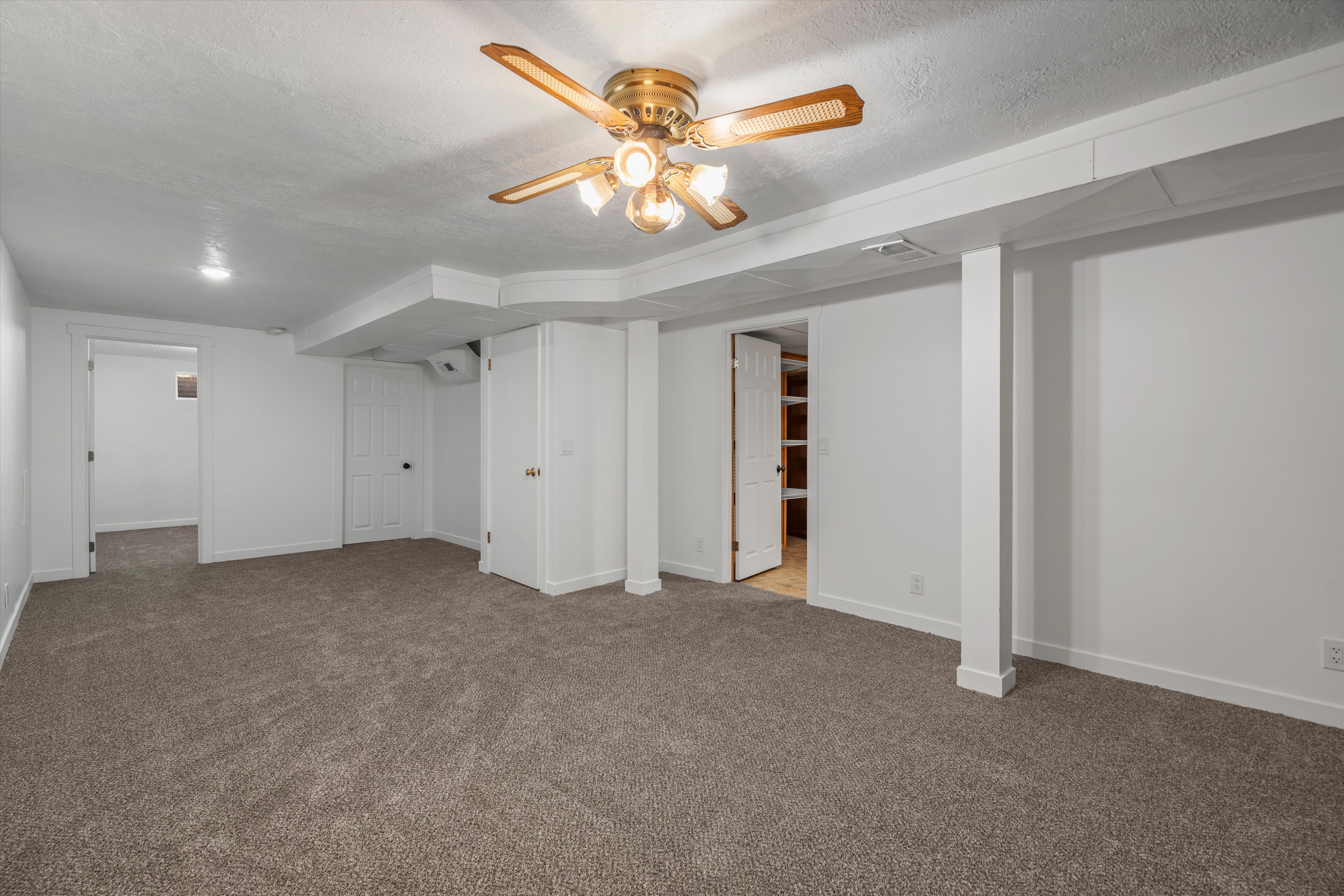 Spacious carpeted room featuring a ceiling fan with integrated lighting, recessed lighting, white walls, and white trim
