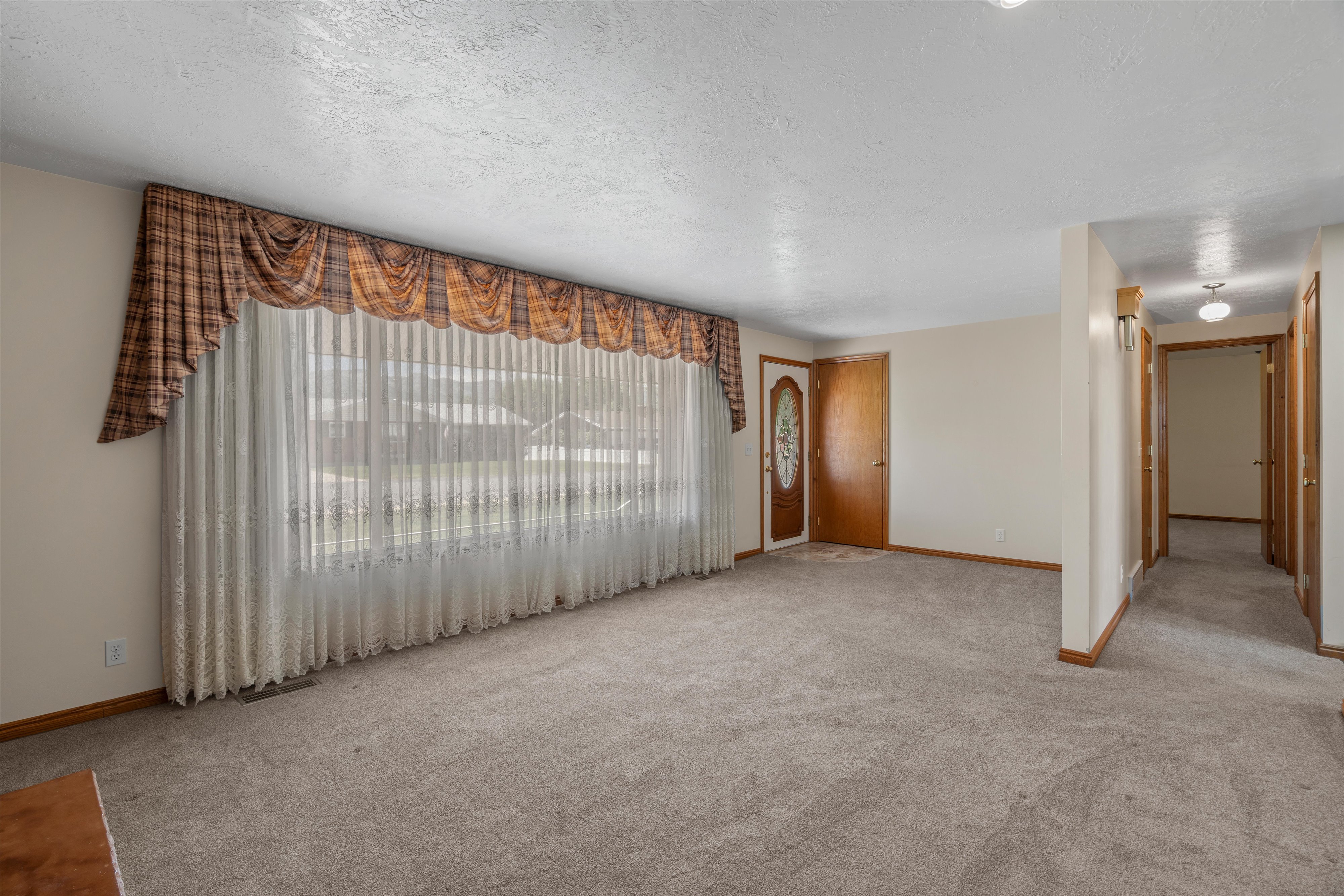 Spacious interior room with neutral carpeting and light-colored walls