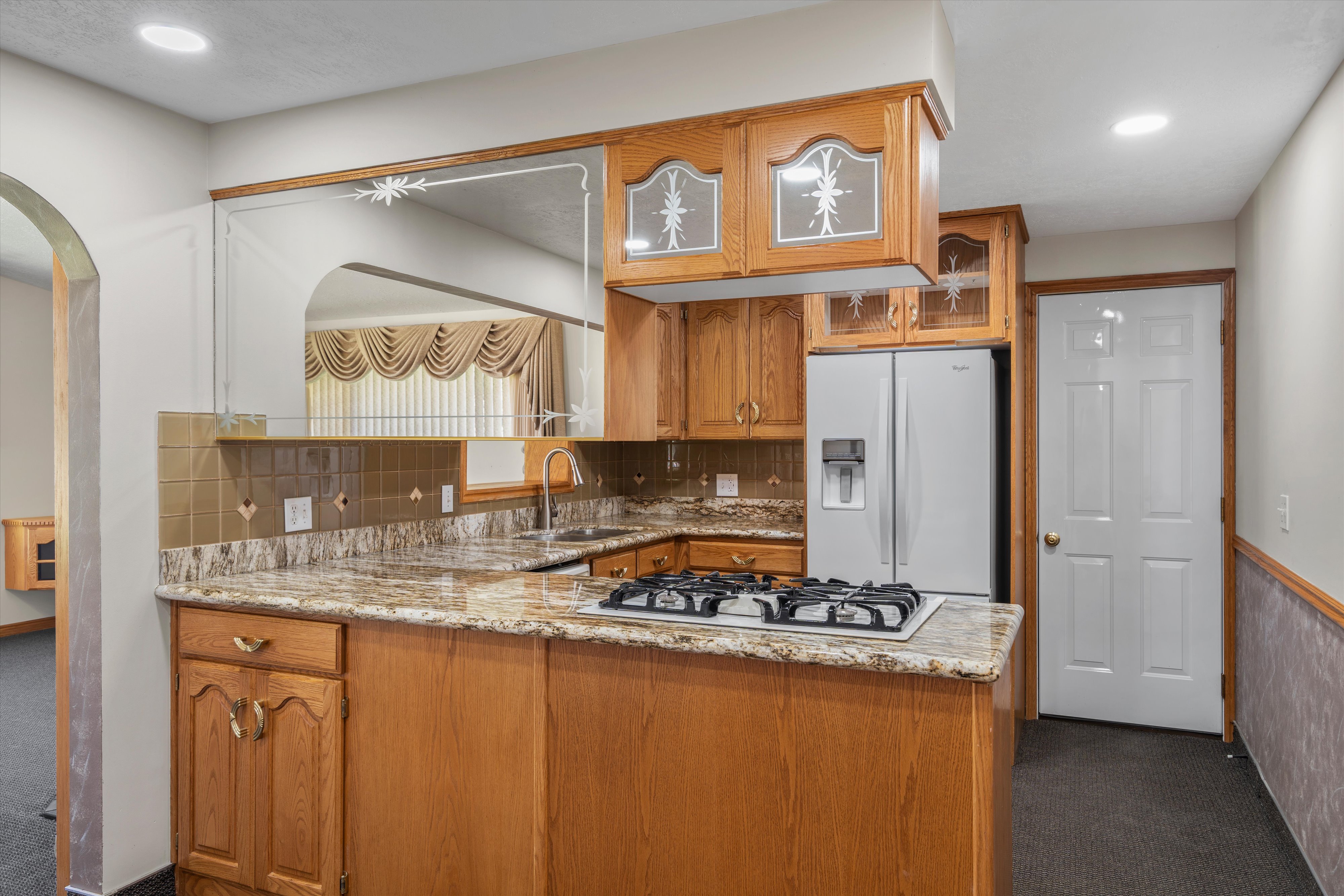 Kitchen featuring light wood cabinetry, granite countertops, a built-in gas cooktop, and a stainless steel side-by-side refrigerator