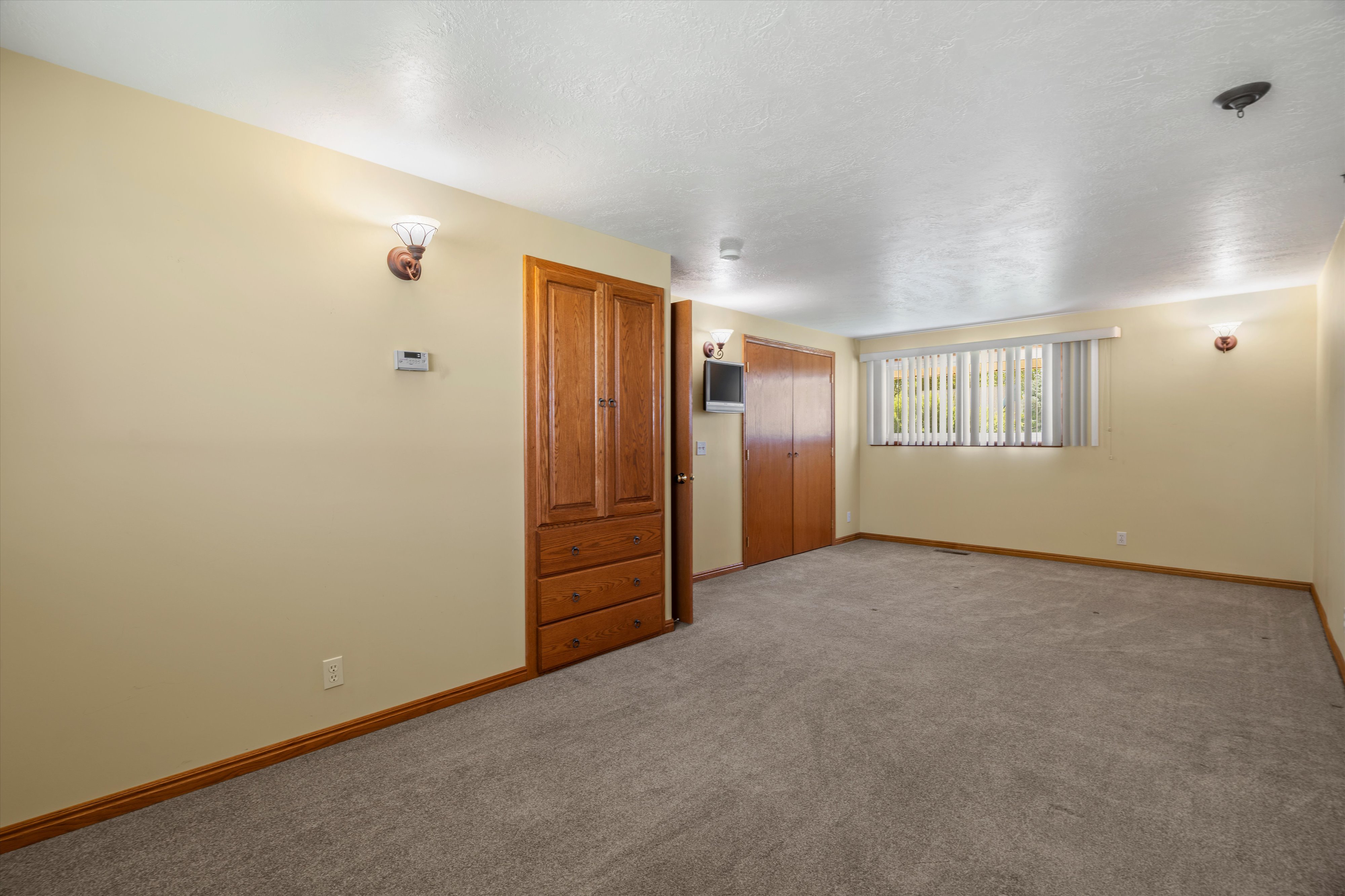 Spacious room featuring neutral wall tones and a textured carpet