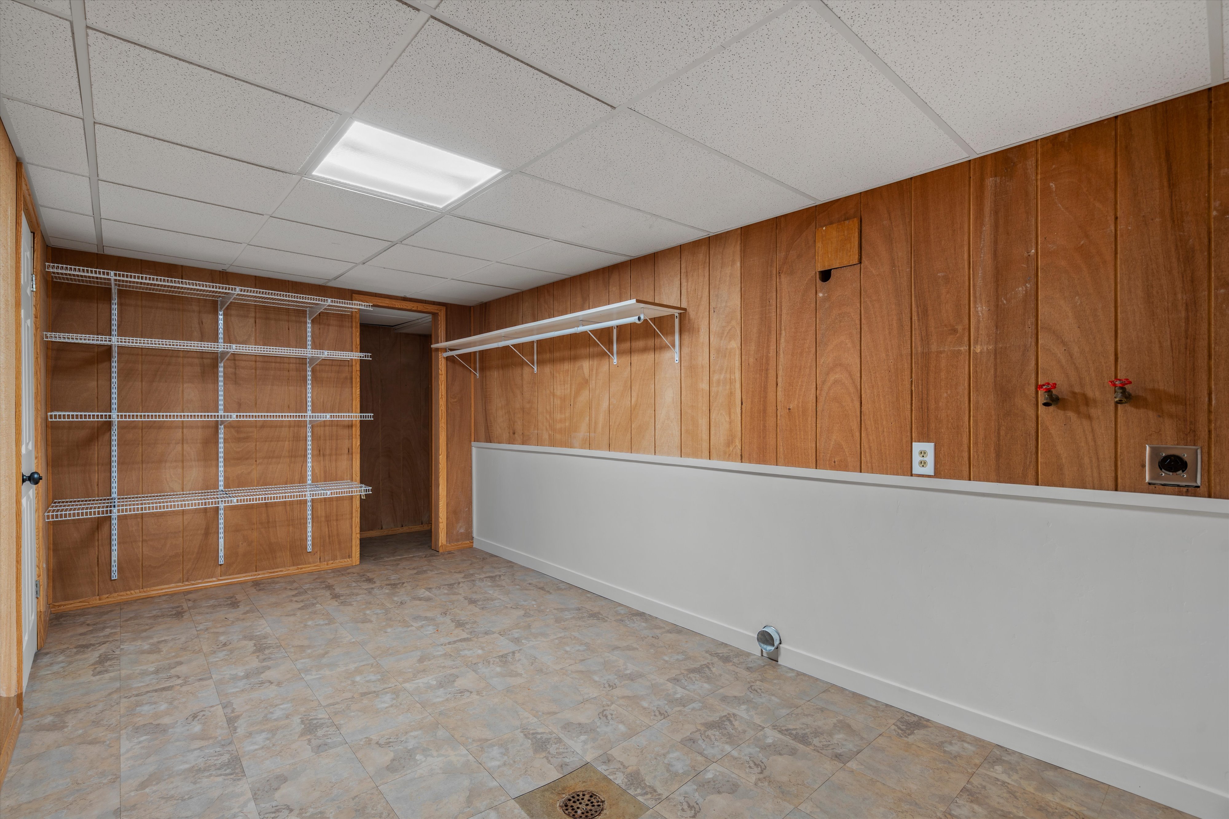 Utility room with wood-finish paneling, white wainscoting, and tile-finish flooring