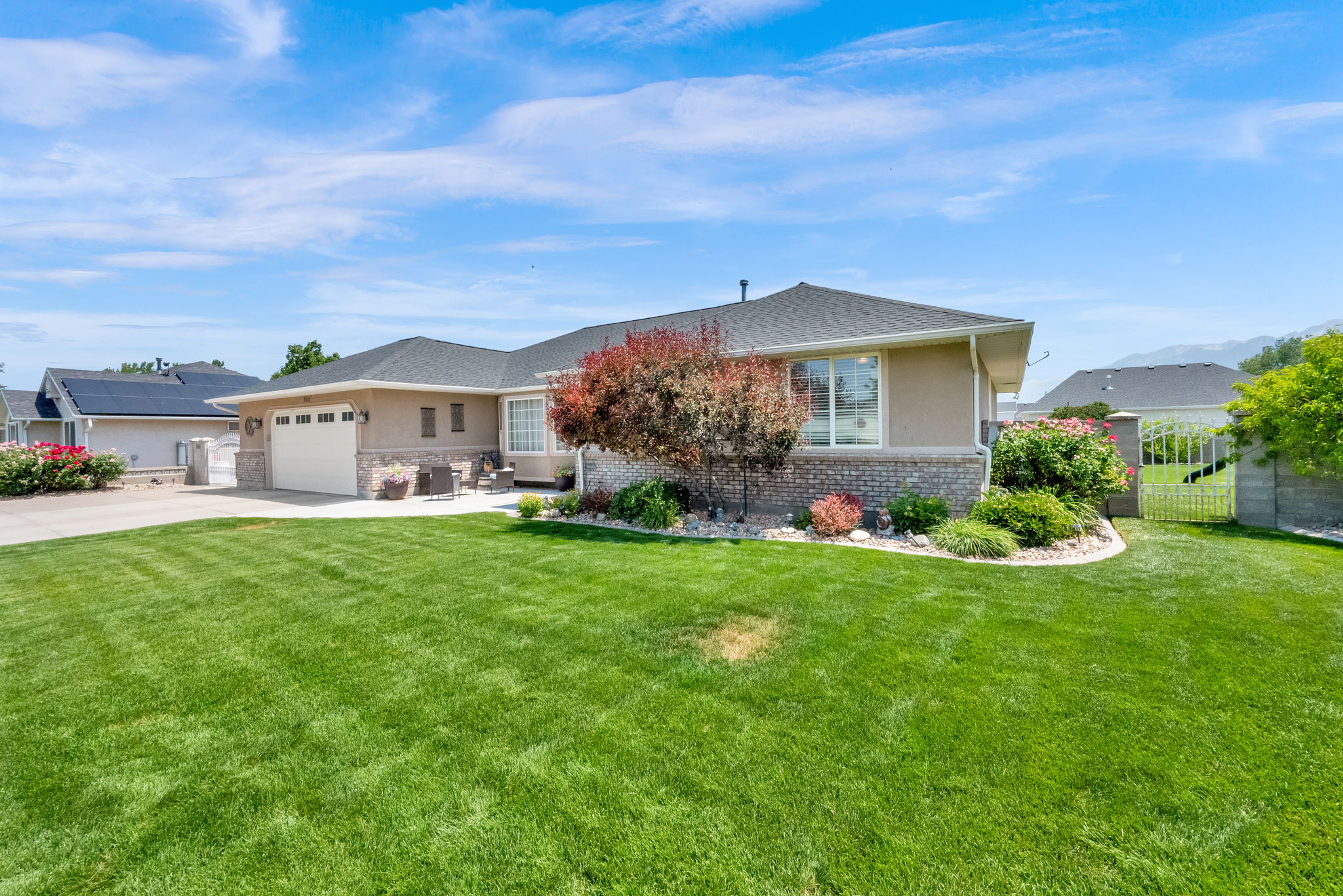 Single-story residence featuring a two-car garage, stone and stucco exterior, bay window, and a dark shingle roof