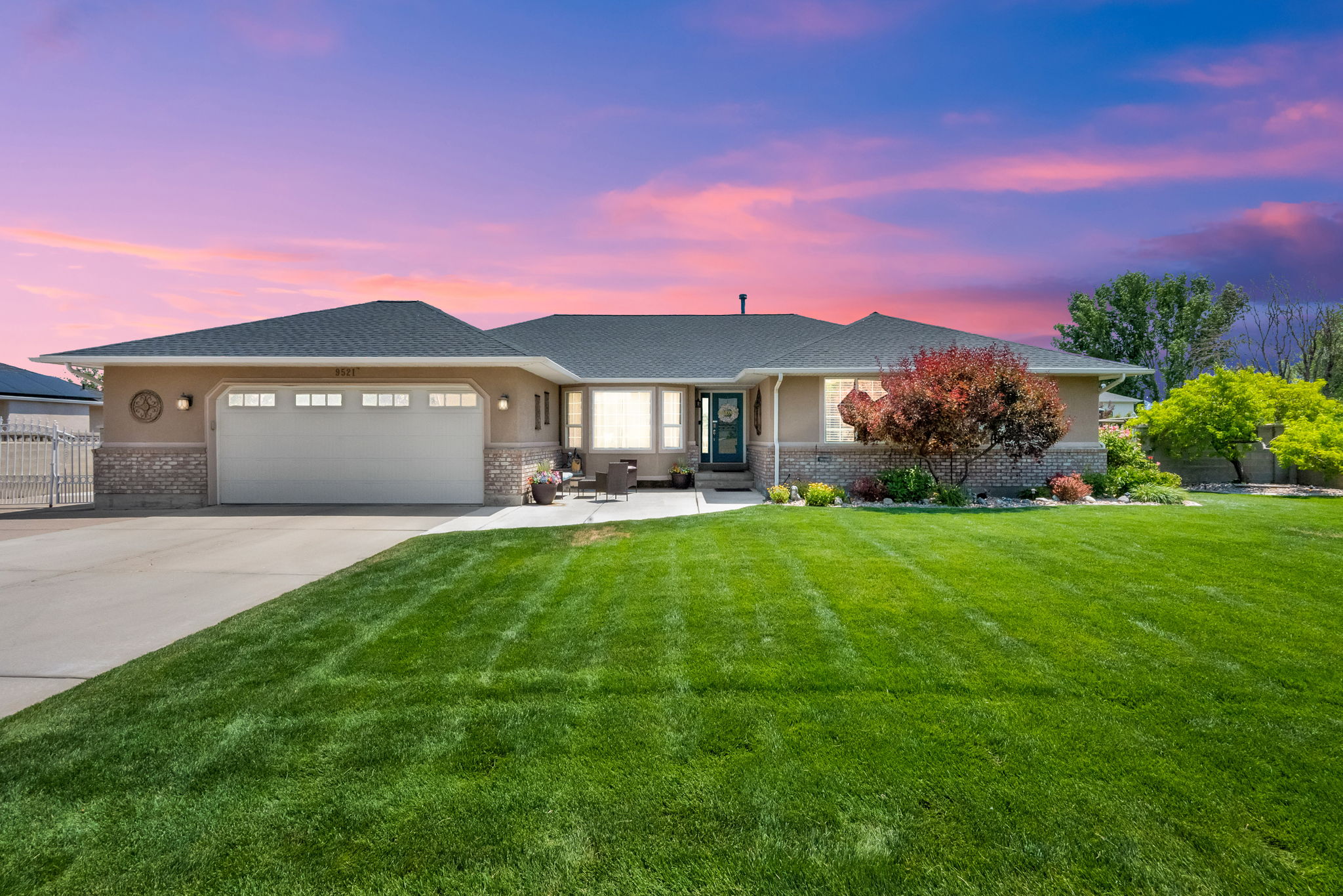 Ranch-style exterior with a two-car garage, partial stone facade, and a dark asphalt shingle roof