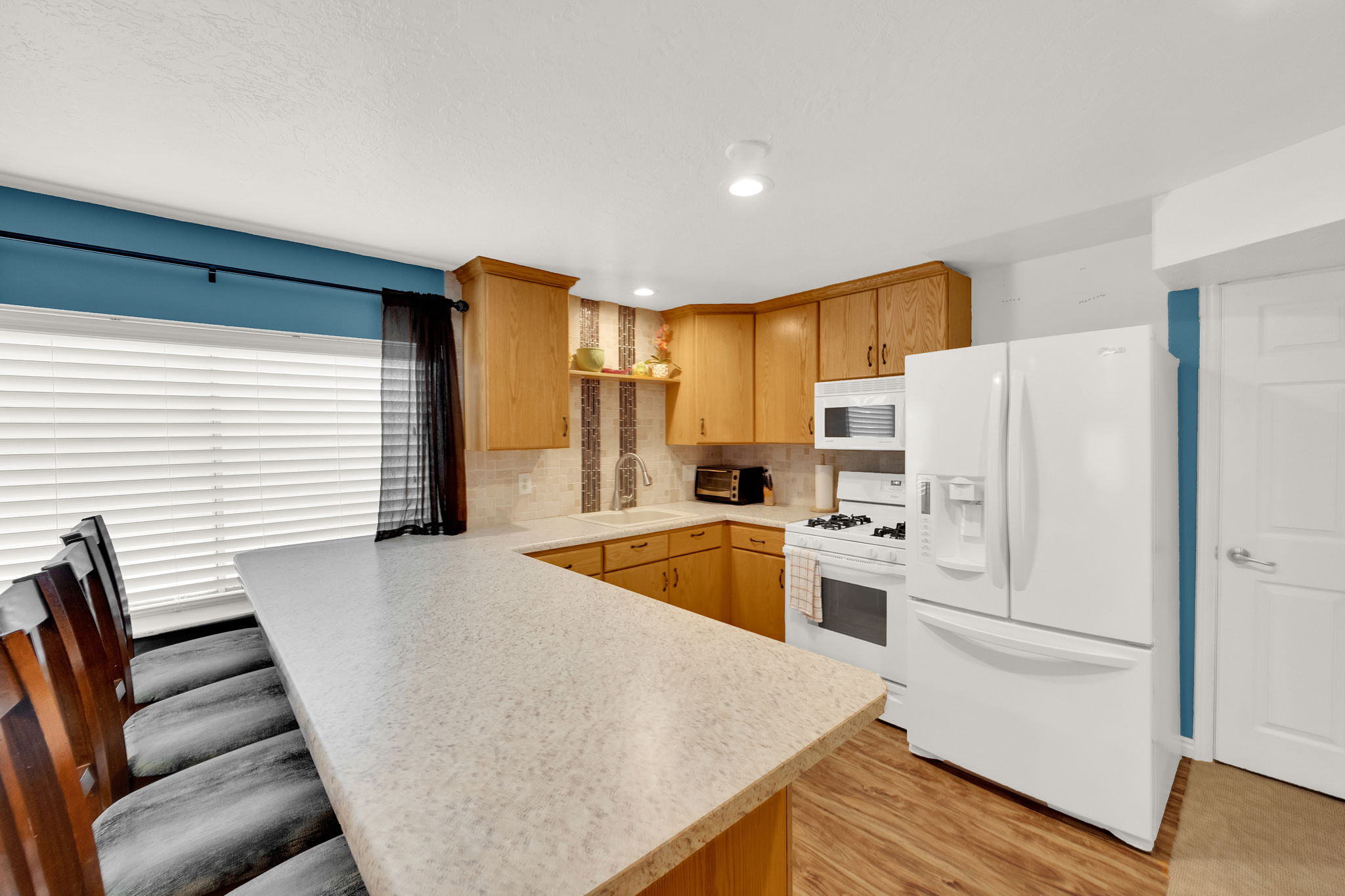 Kitchen featuring a breakfast bar with stone-finish countertops, wood-finish flooring, and light wood cabinetry