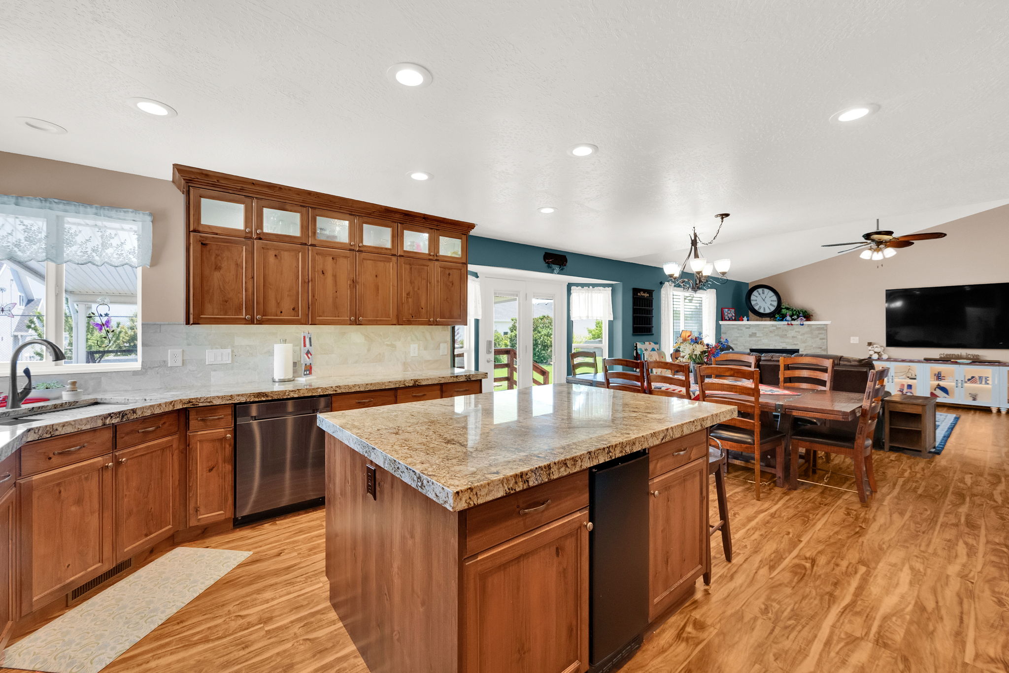Open concept living area featuring a kitchen island with stone countertop, stainless steel appliances, and wood-finish flooring