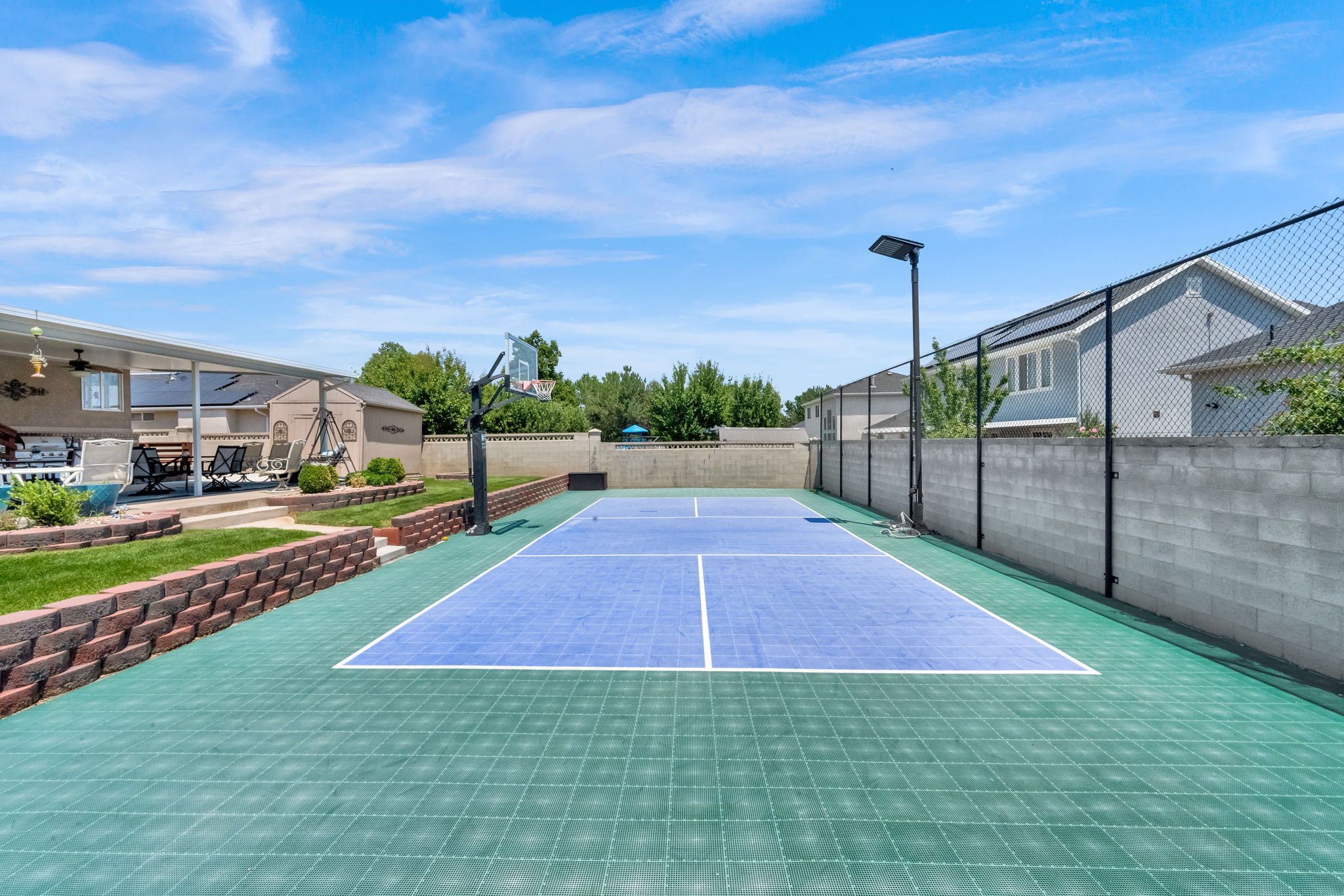 Multi-sport court featuring a basketball hoop and dedicated lighting