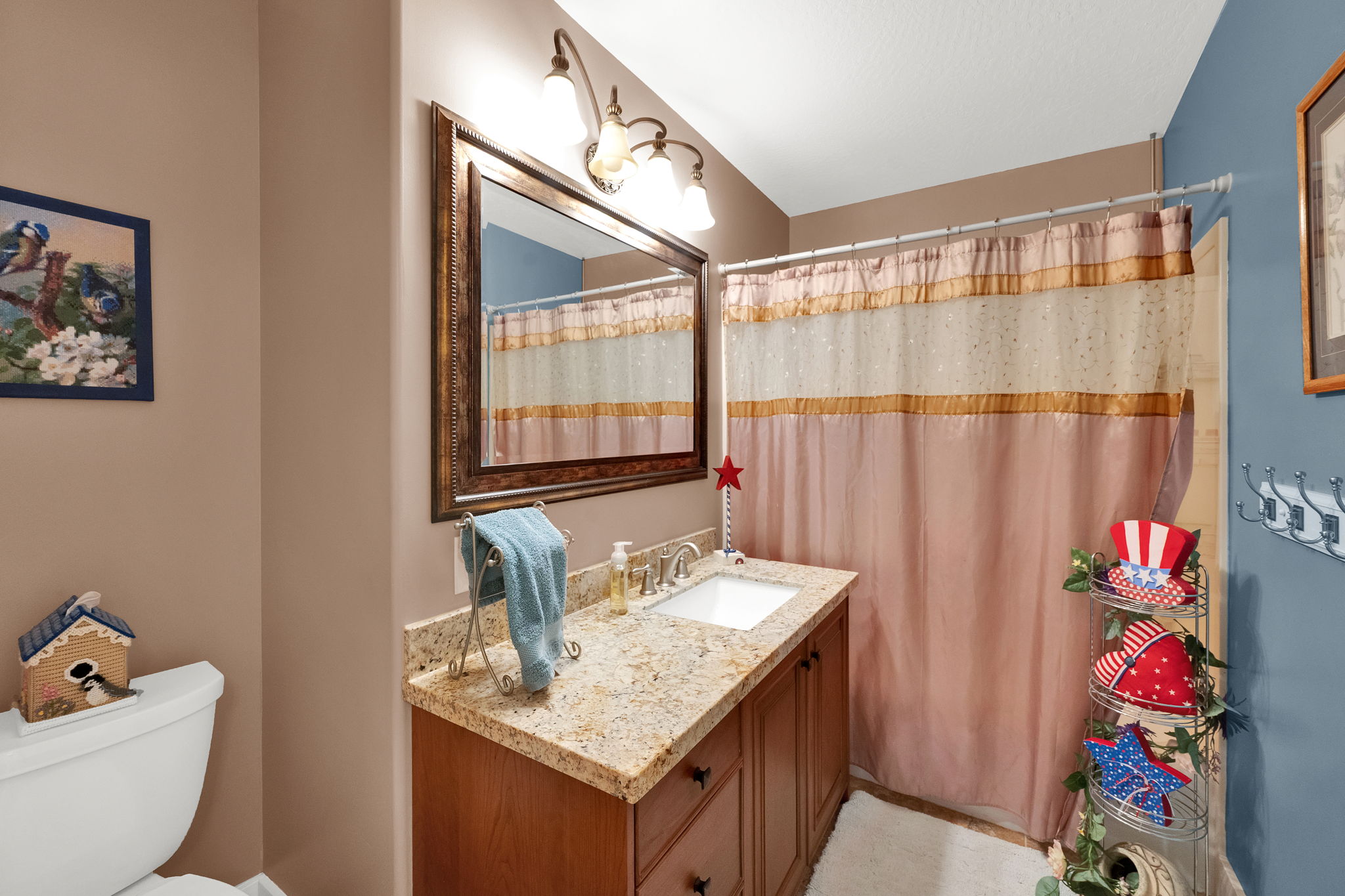 Bathroom featuring a wood vanity with a stone-finish countertop and integrated sink, a framed mirror, and an overhead light fixture