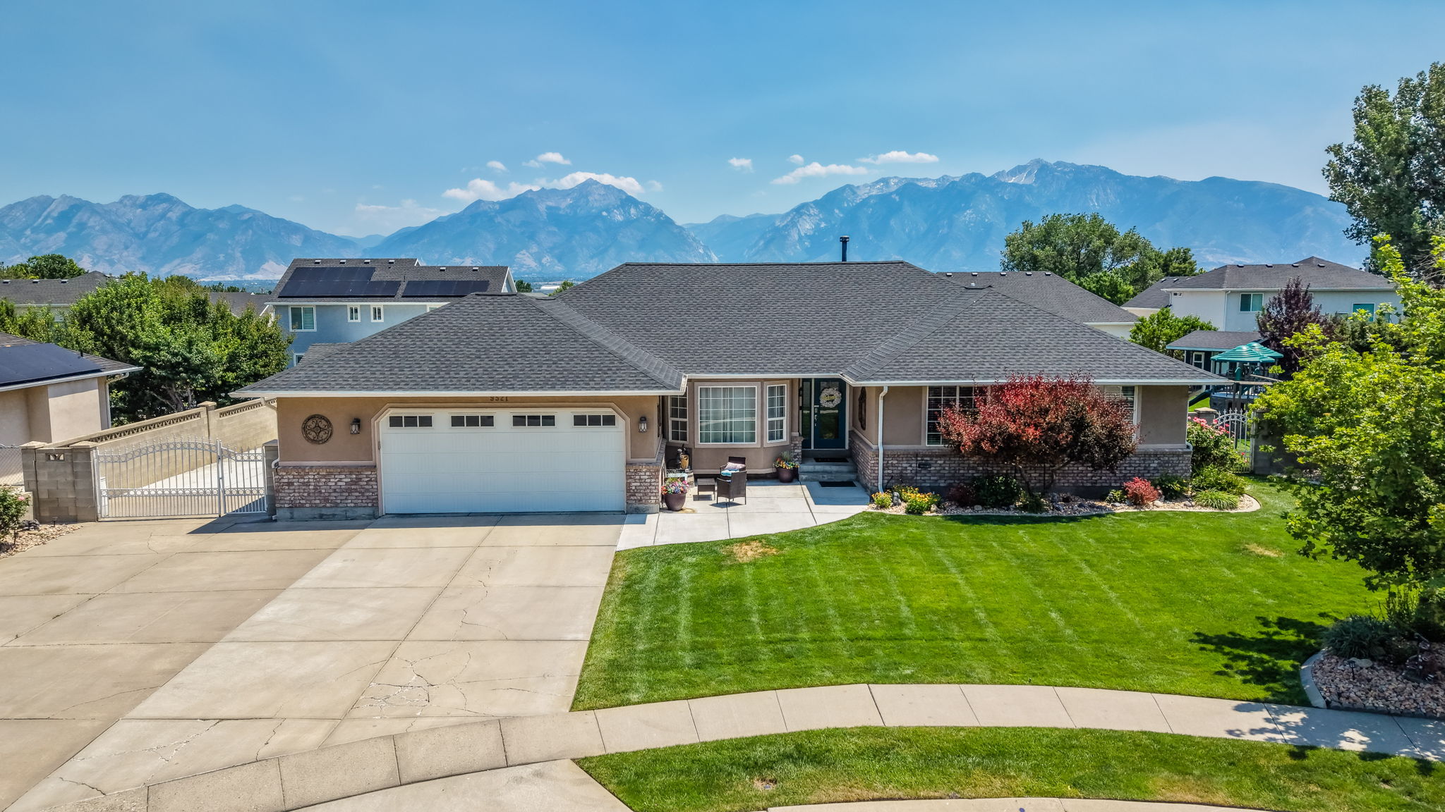 Single-story residence featuring a two-car garage, manicured front lawn, and mature landscaping