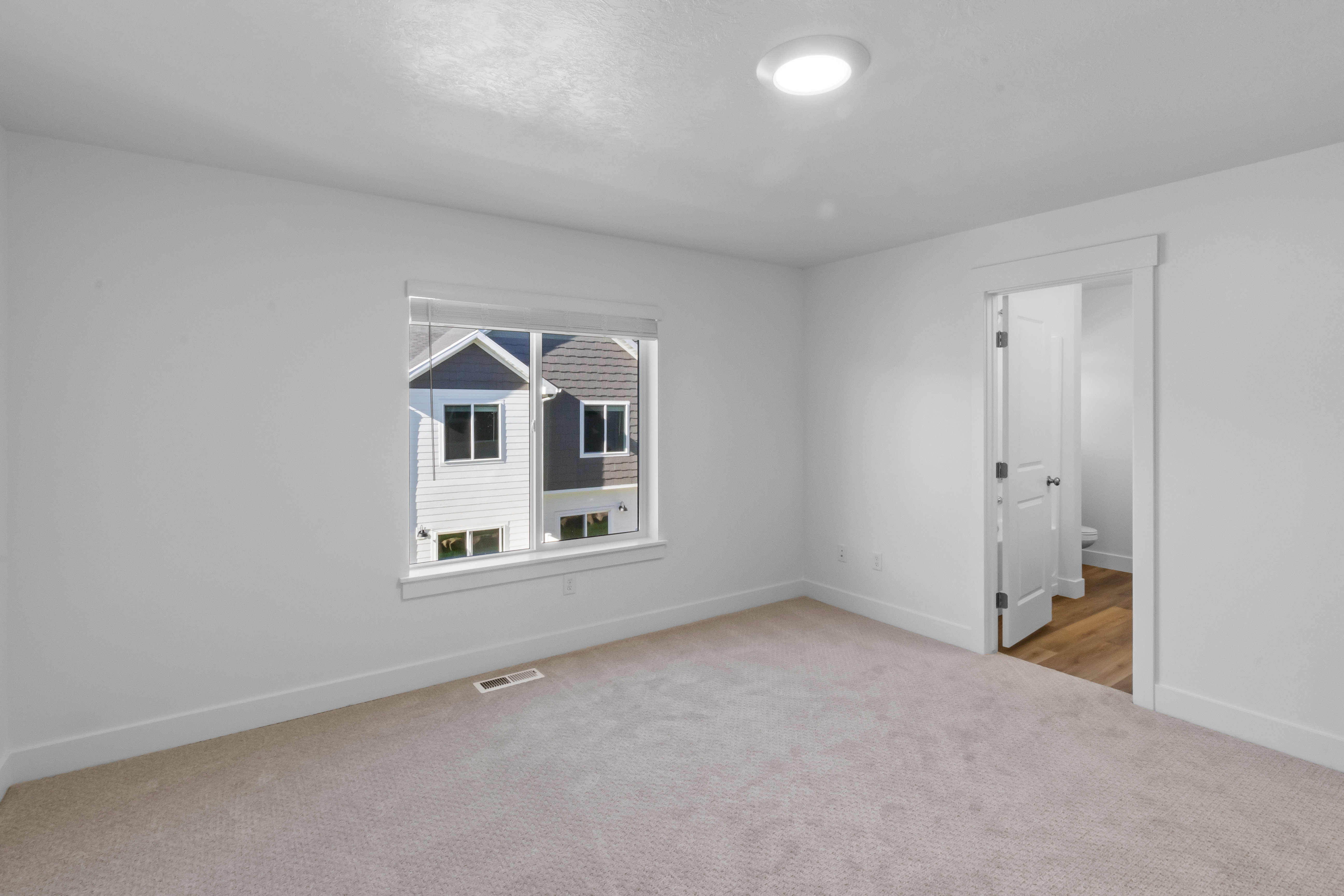 Room featuring neutral-toned carpeting, a recessed ceiling light, and a window with white blinds