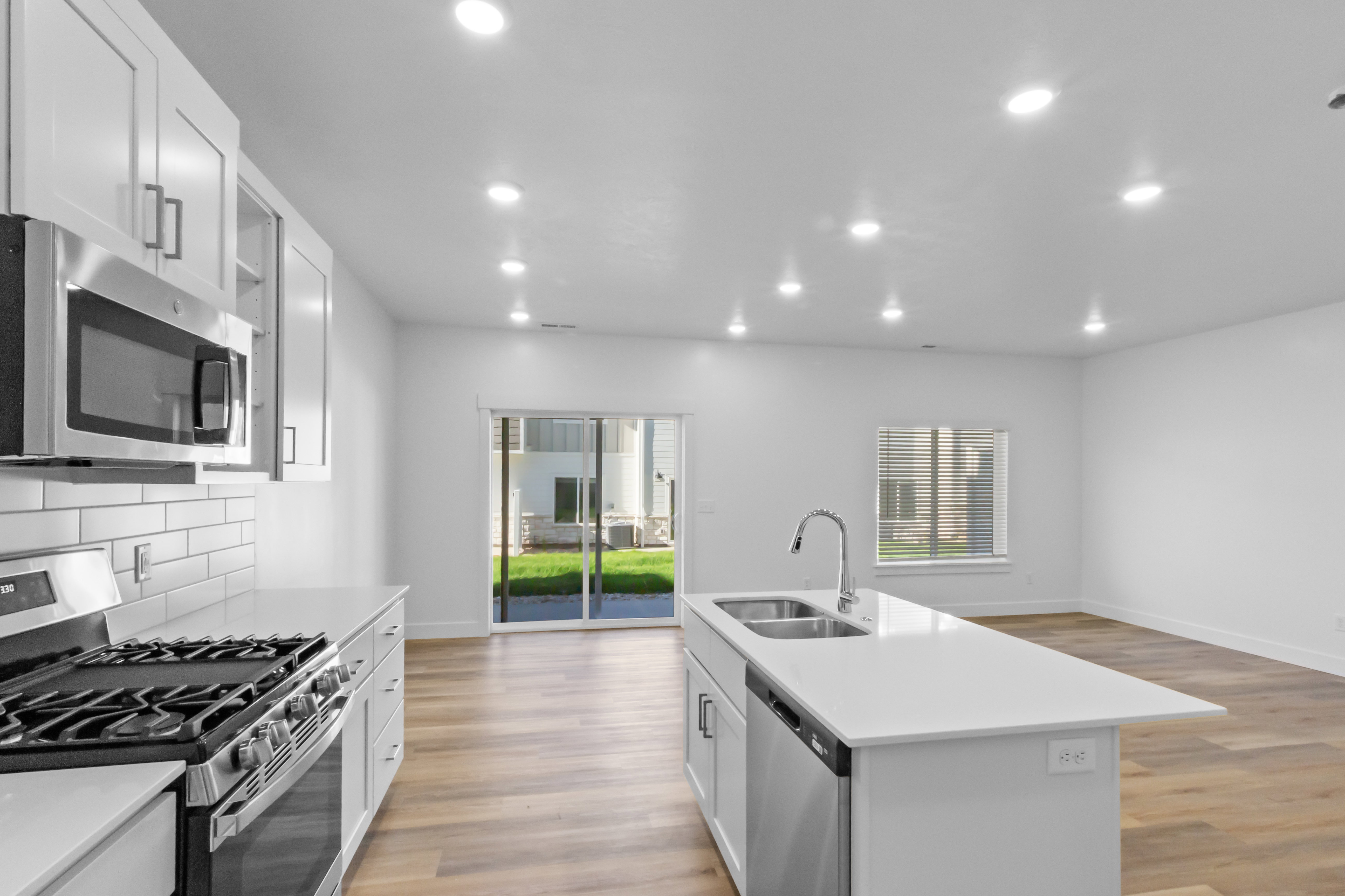 Contemporary kitchen featuring white cabinetry, stainless steel appliances, white subway tile backsplash, and a central island with an integrated double sink
