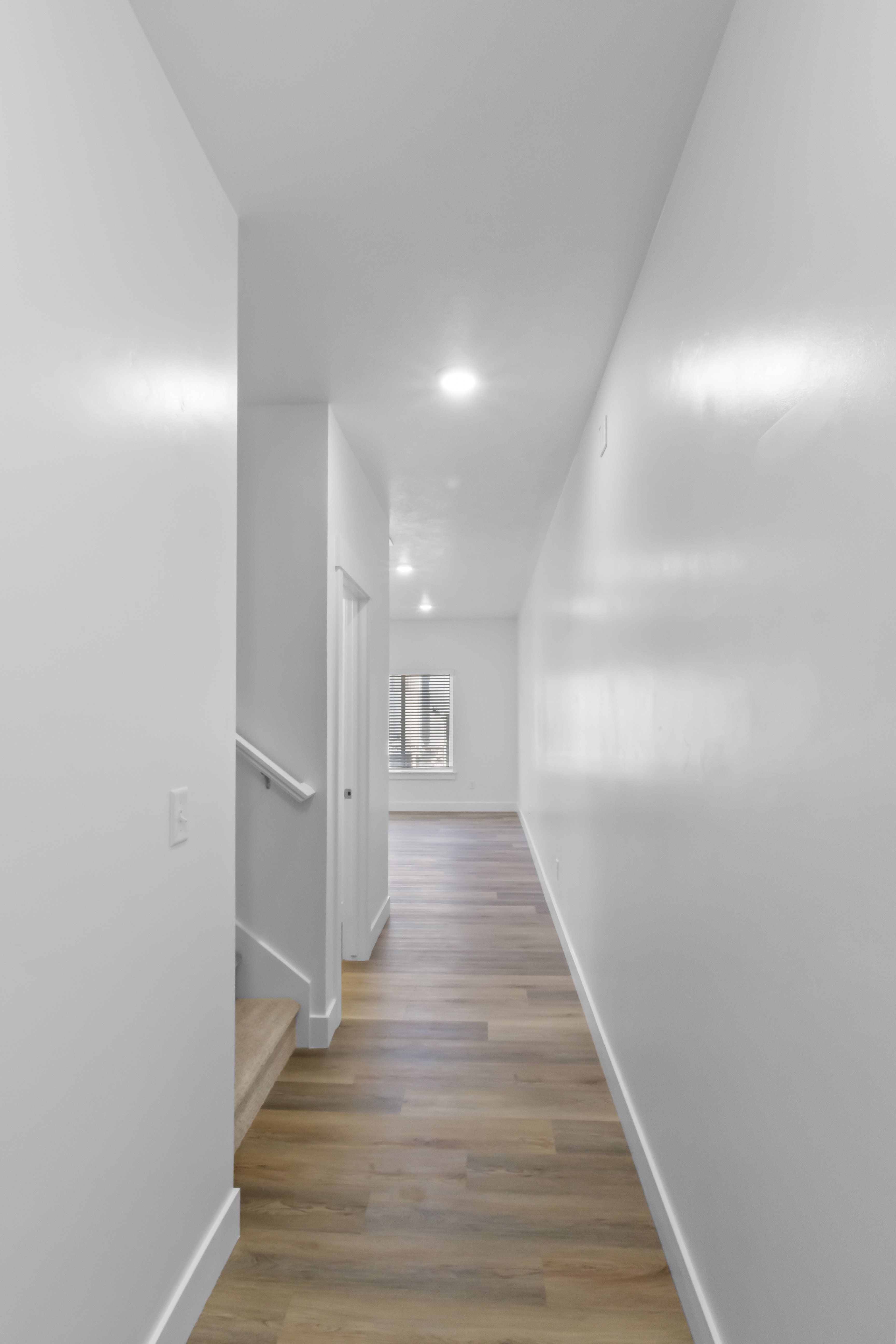 Hallway featuring wood-finish flooring, white walls, recessed ceiling lighting, and white baseboards