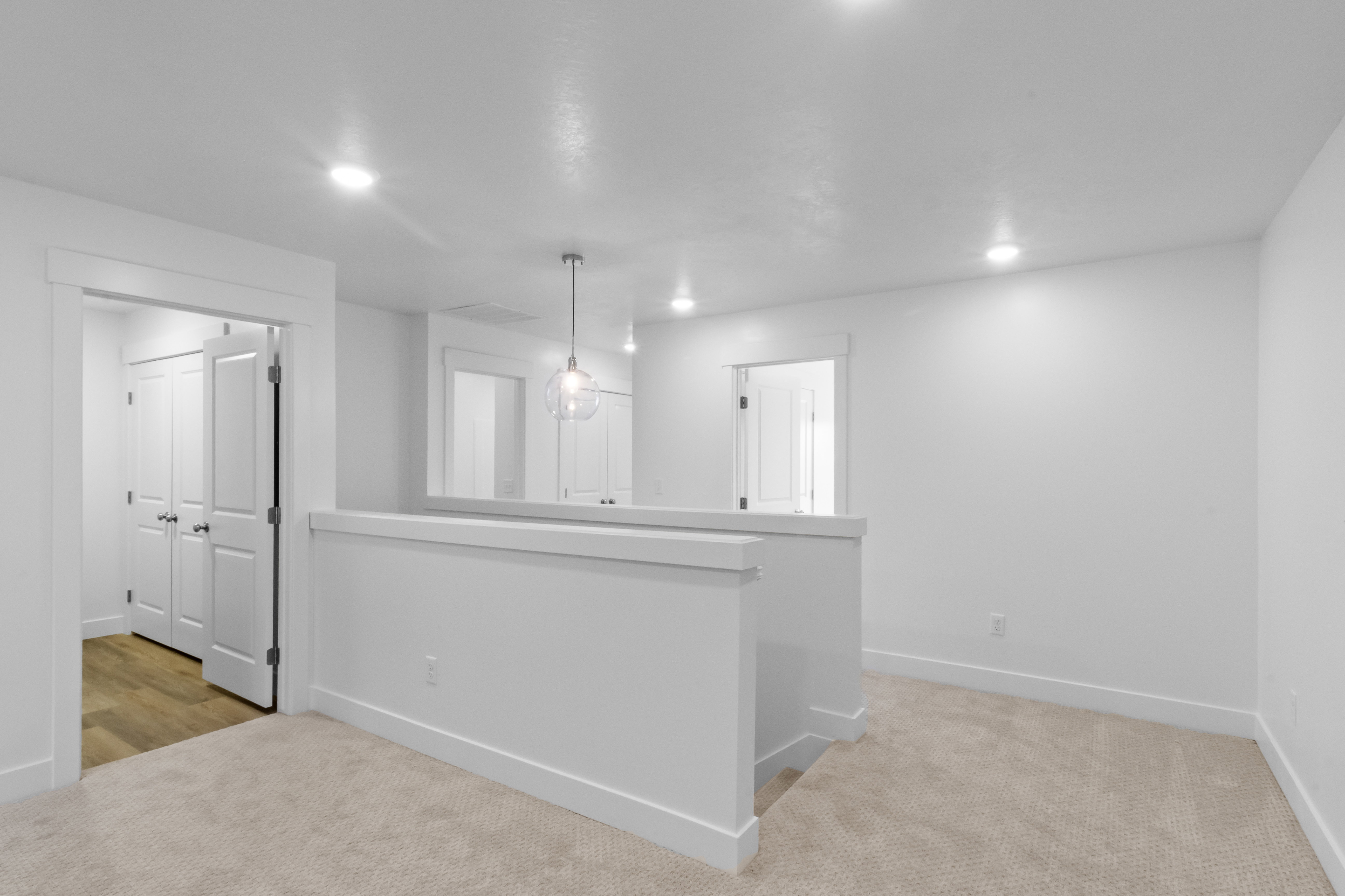 Open landing area featuring neutral-toned carpeting, white walls, and recessed ceiling lighting