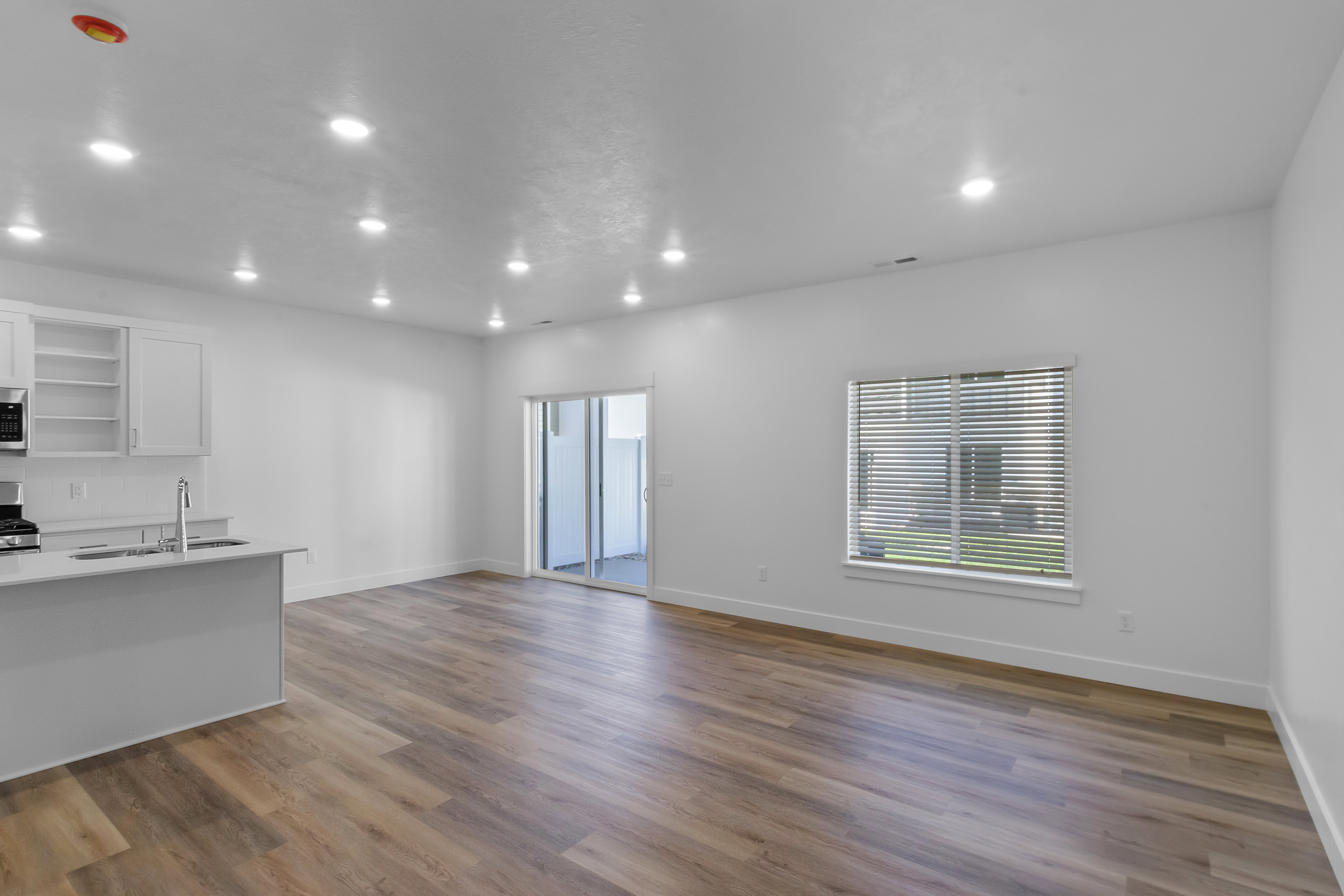 Open-concept main living area with wood-finish flooring, recessed lighting, and a sliding glass door
