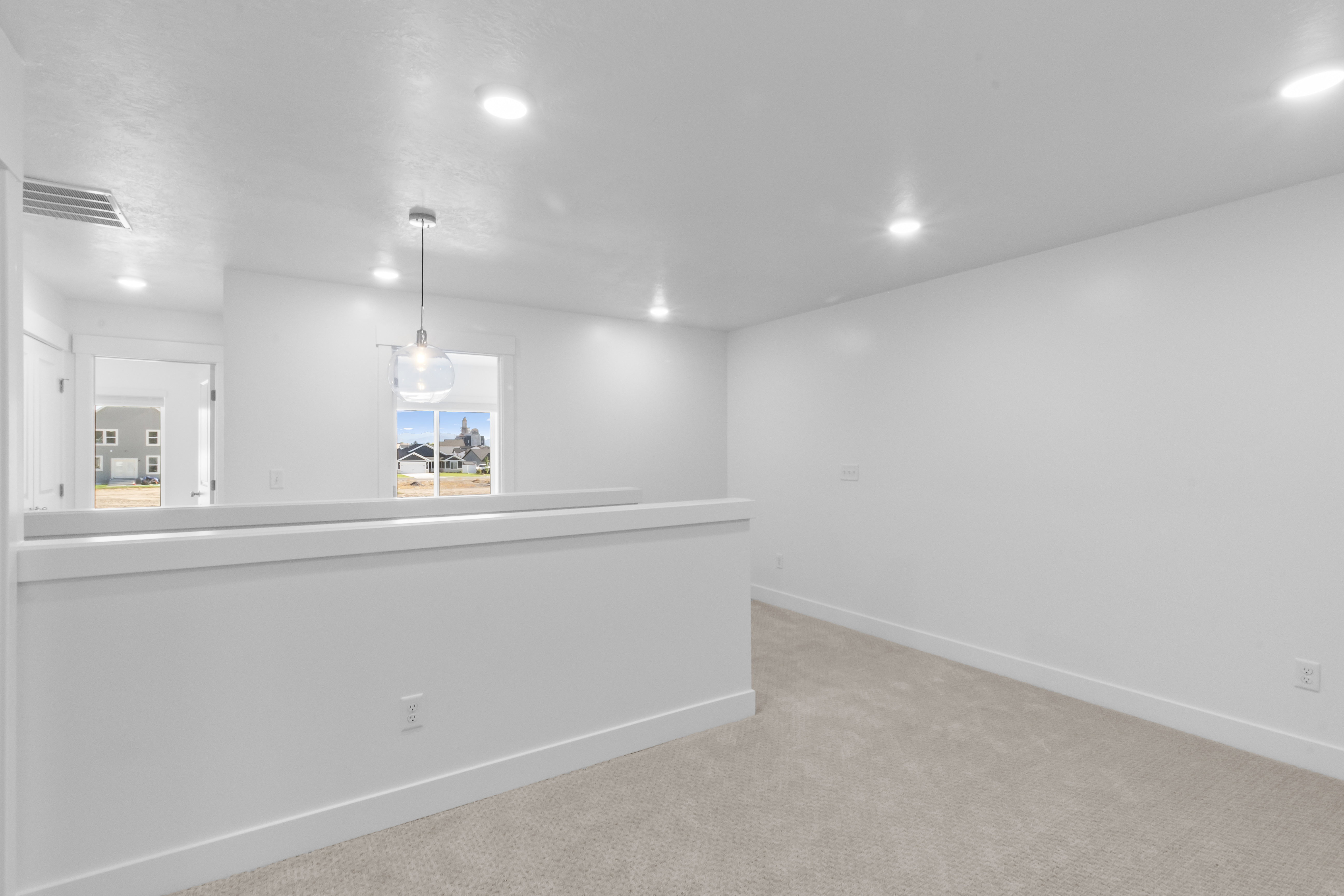 Open loft space featuring recessed lighting and a contemporary pendant fixture